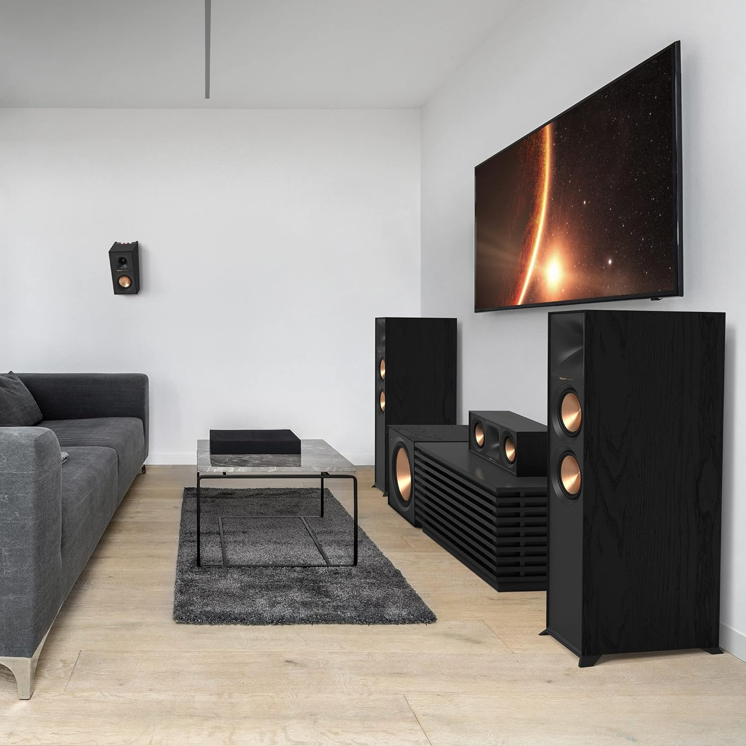 Wohnzimmer mit Lautsprechern, TV, Couchtisch und Teppich auf hellem Holzboden.