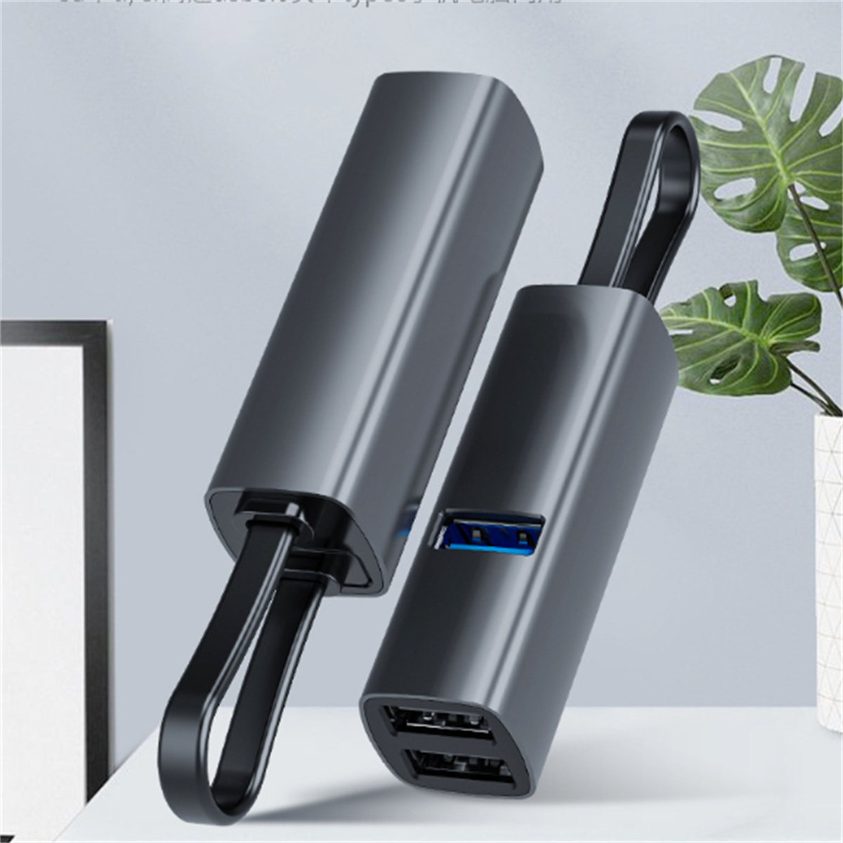 Zwei schwarze USB-Ladegeräte mit Griff und USB-Anschluss, platziert auf einer Oberfläche mit Pflanze.