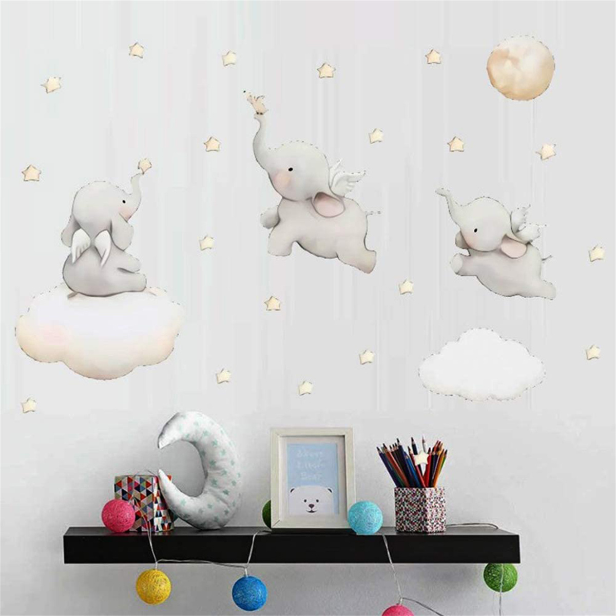 Wanddeko mit Elefanten, Sternen und Wolken. Regal mit Spielzeug und Deko darunter.