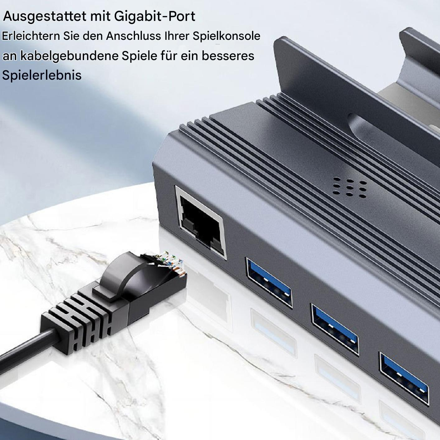 Ein grauer Hub mit angeschlossenem Netzwerkkabel und USB-Anschlüssen. Der Hub befindet sich auf einer weißen Oberfläche.