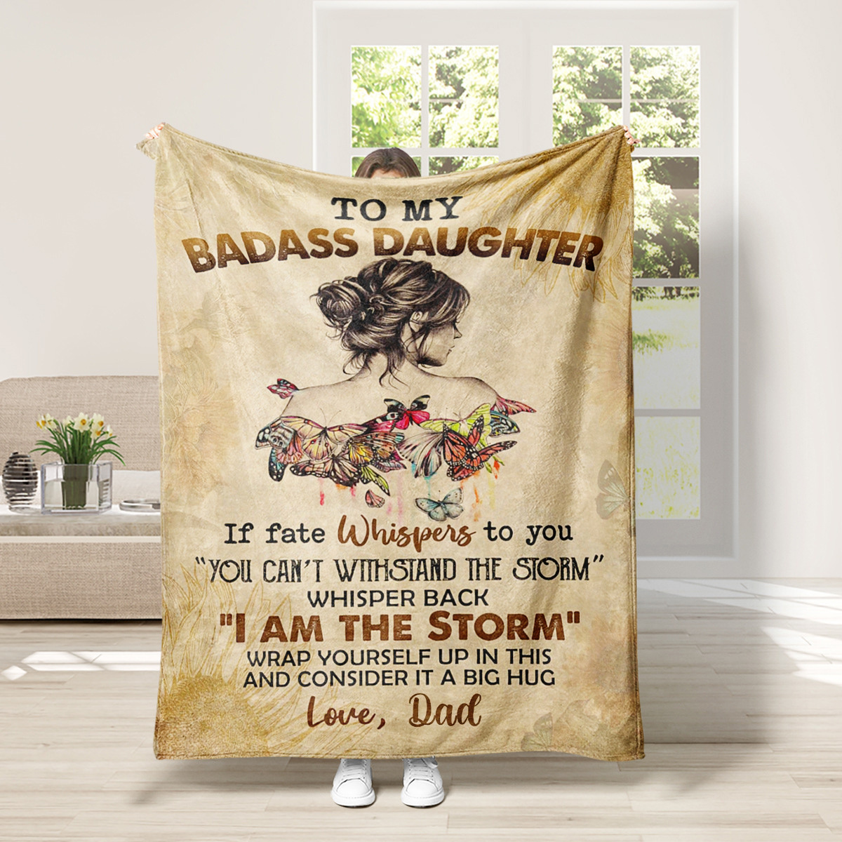 Eine Decke mit Text: 'TO MY BADASS DAUGHTER'. Bild des Rückens einer Frau und Schmetterlinge.