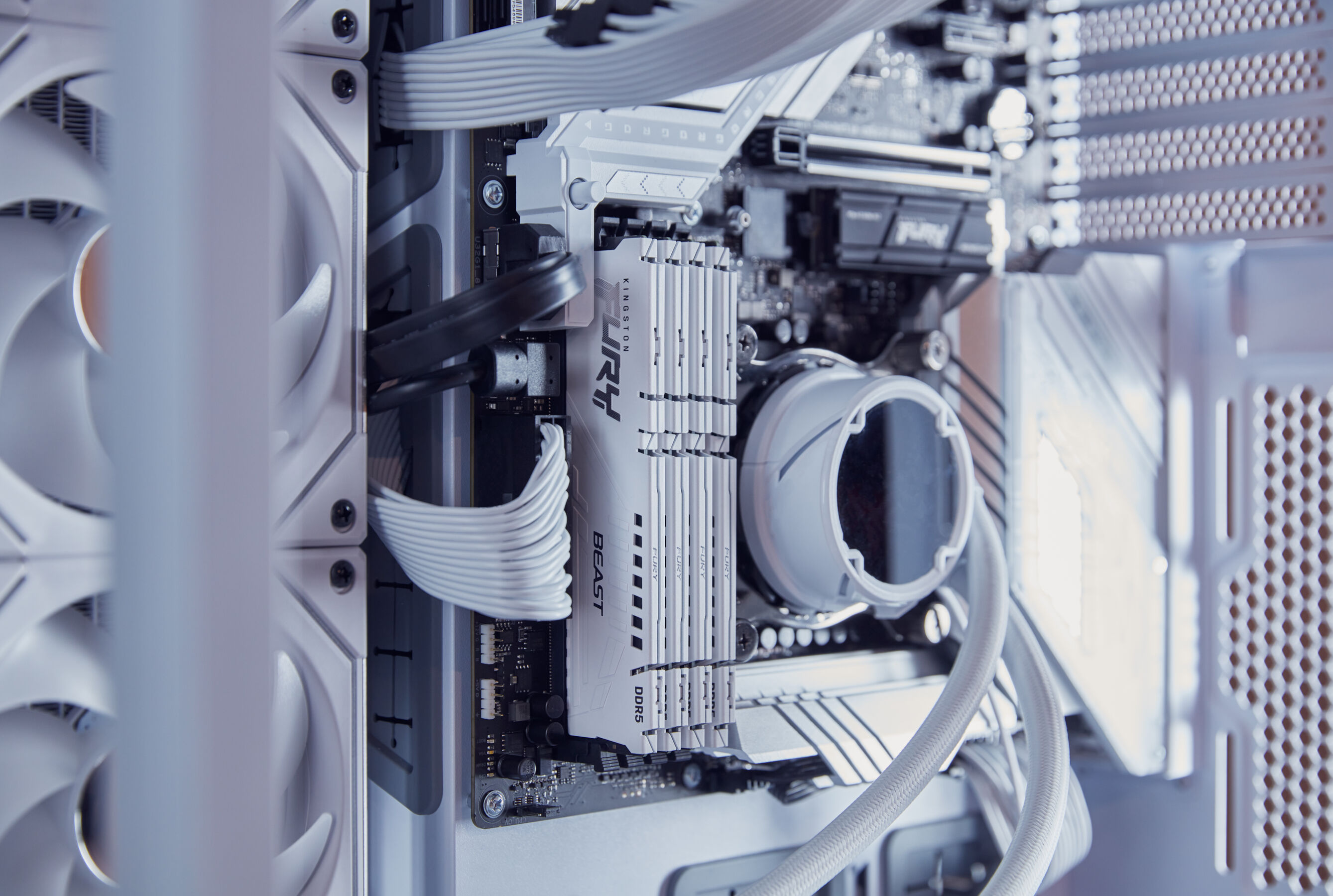 Wewnątrz obudowy komputera widoczne są kości RAM i inne komponenty. Obecne są również przewody i wentylatory.