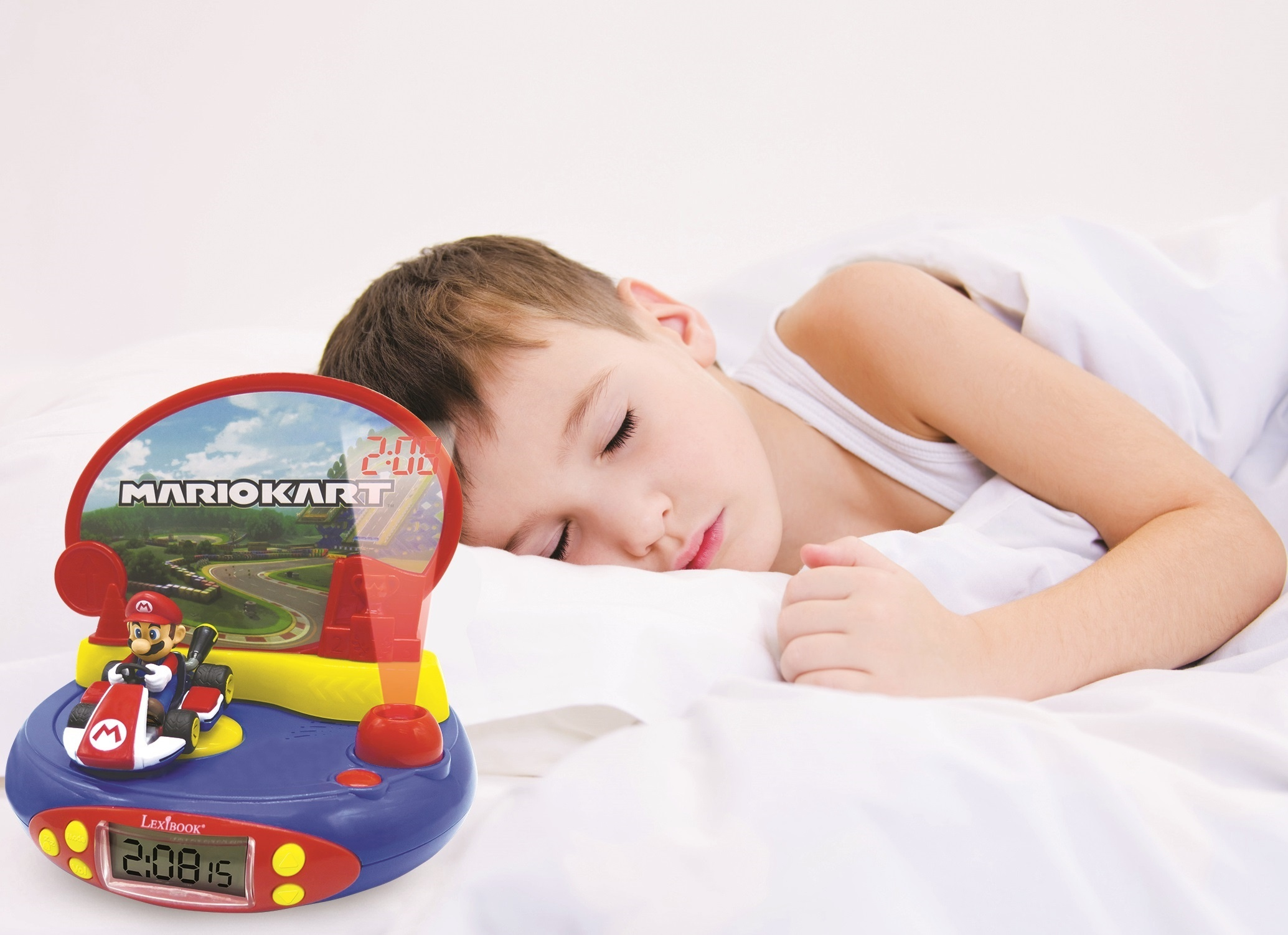 Un niño durmiendo junto a un despertador de Mario Kart. El fondo es una sábana blanca.