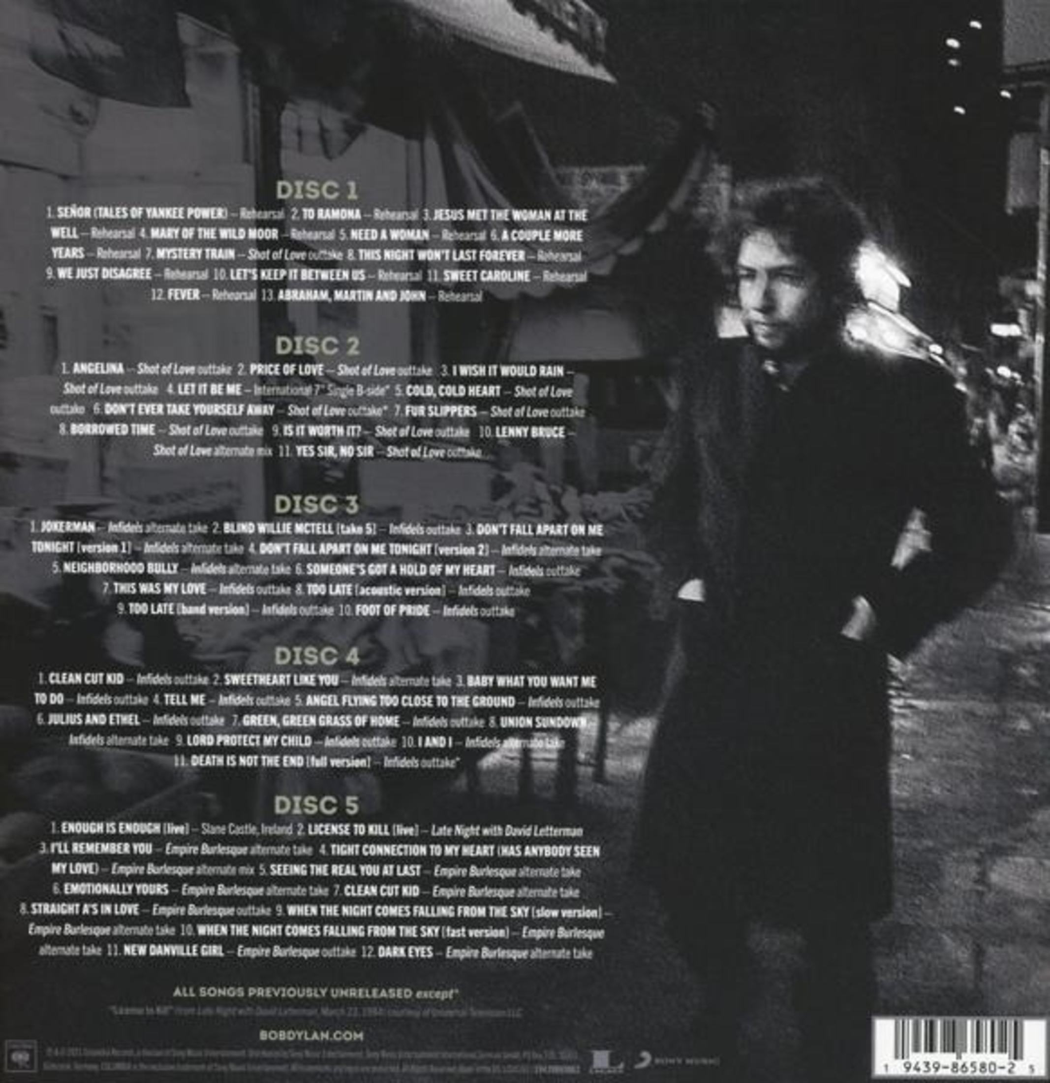 Tekst op de achterkant van een album met songtitels en details. Een man staat rechts.