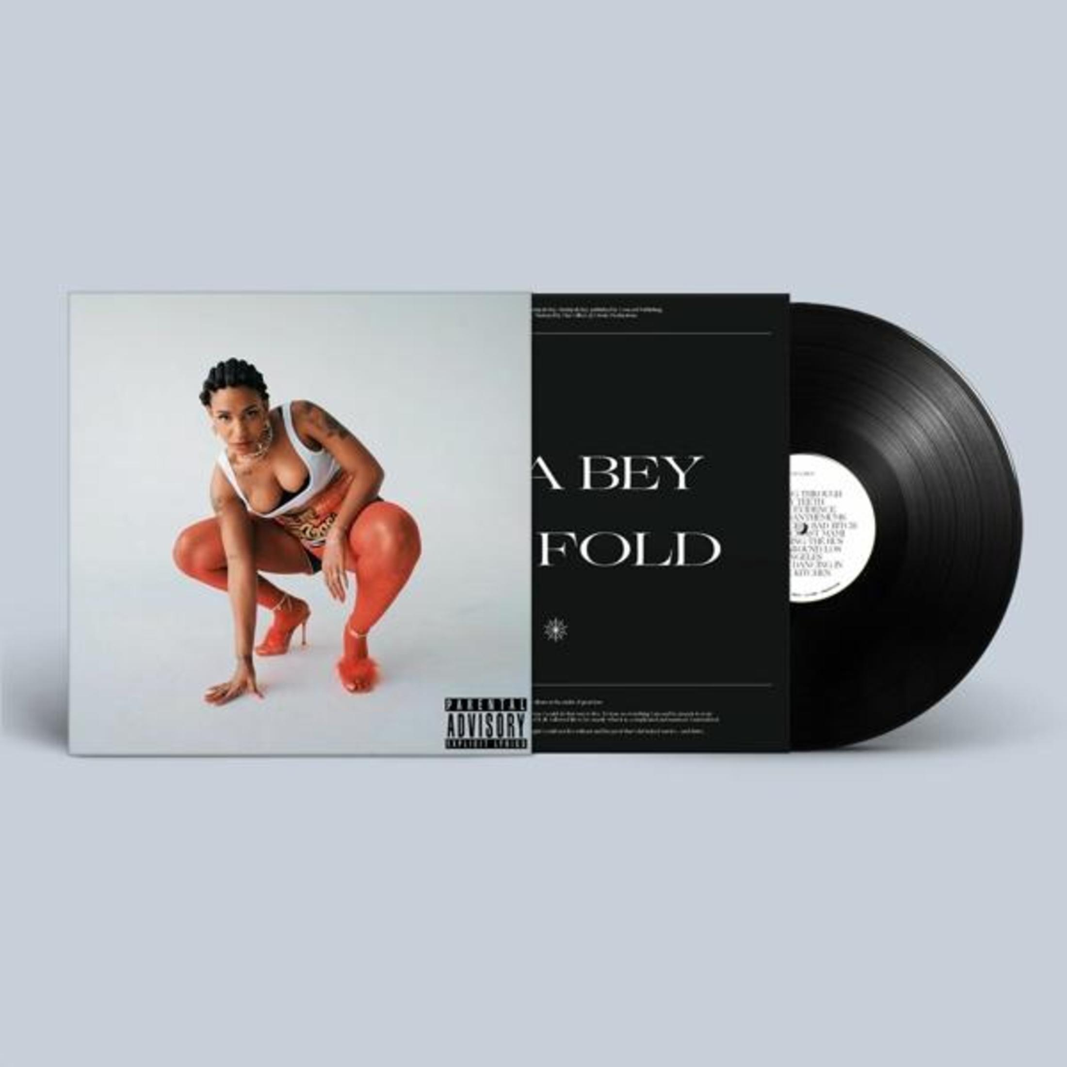 La copertina dell'album mostra una donna con pantaloni e tacchi rossi accovacciata. L'album e il vinile sono a destra.