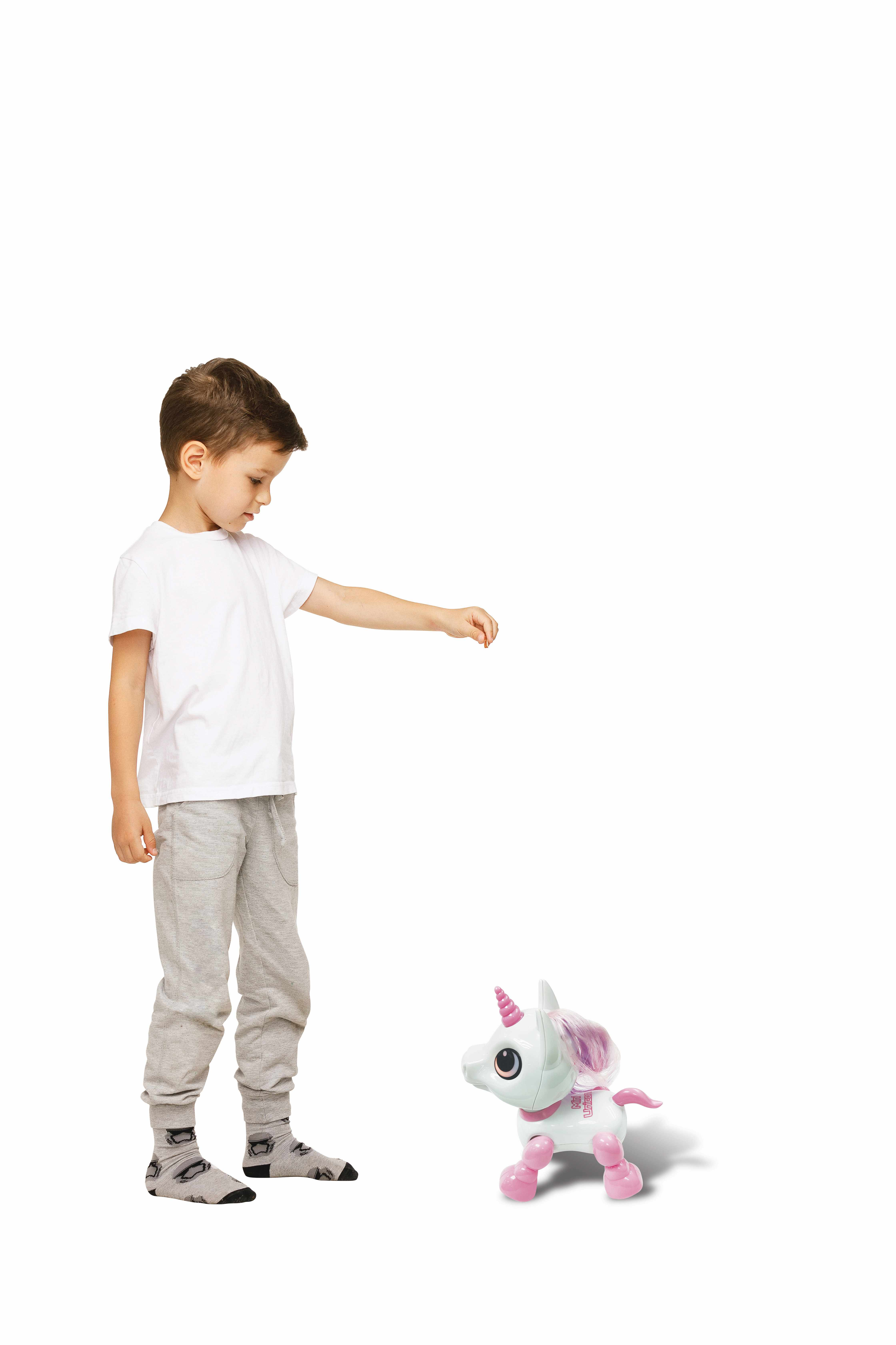 Niño señalando un unicornio de juguete sobre fondo blanco.