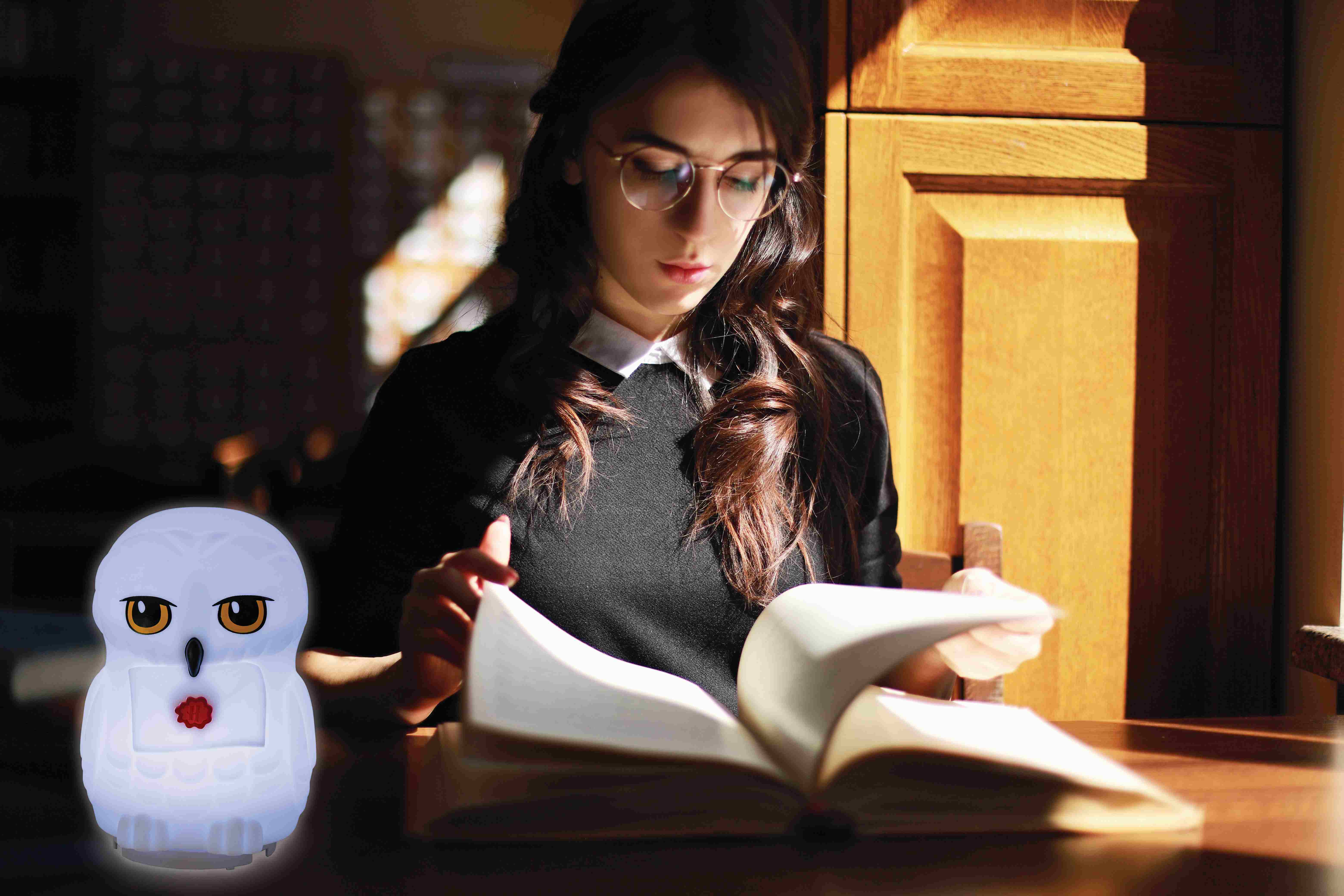 Mujer leyendo libro con lámpara Hedwig. La lámpara es blanca. Escena interior.
