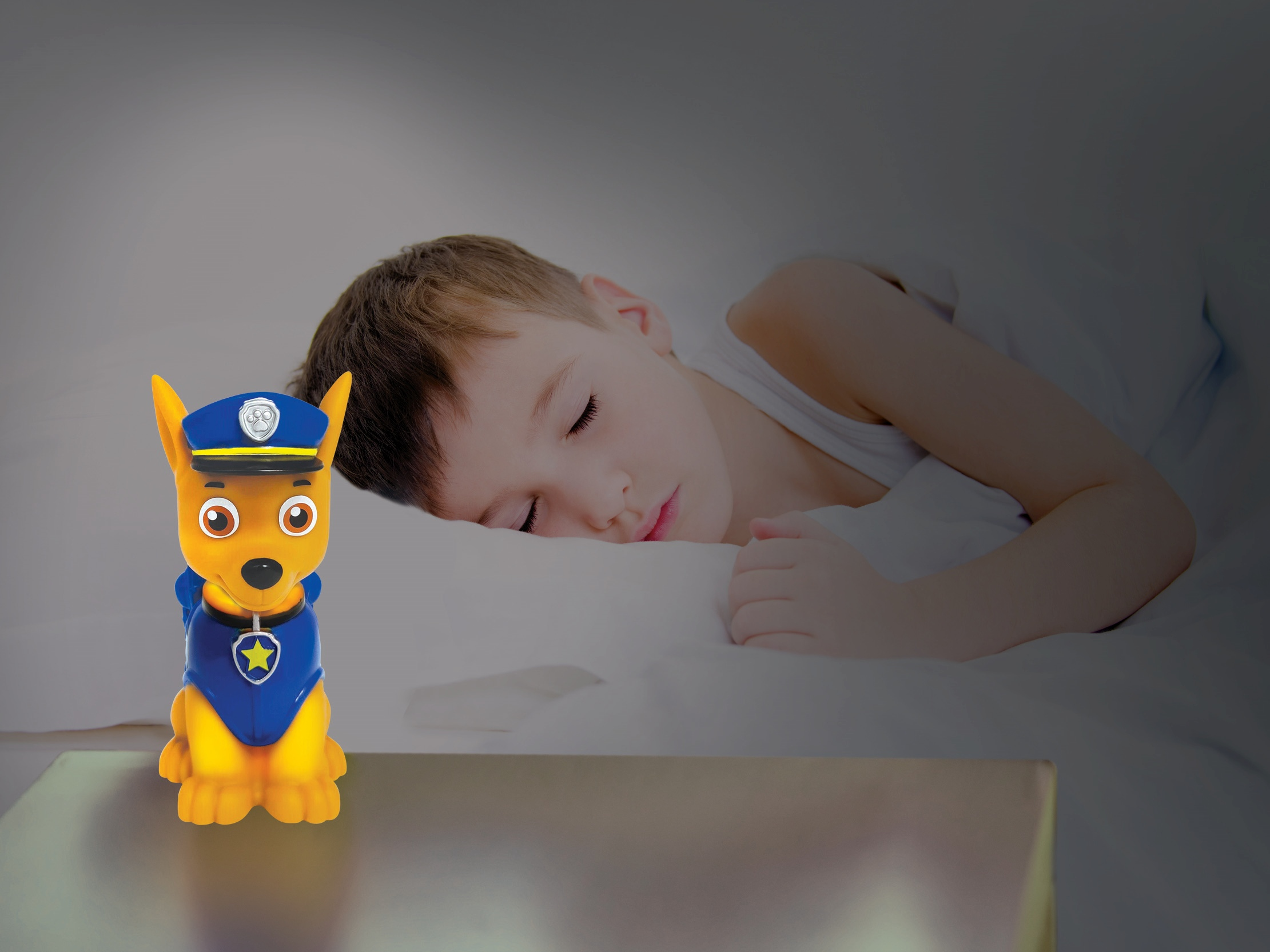 Luz nocturna Chase junto a un niño durmiendo. La luz es un perro de dibujos animados.