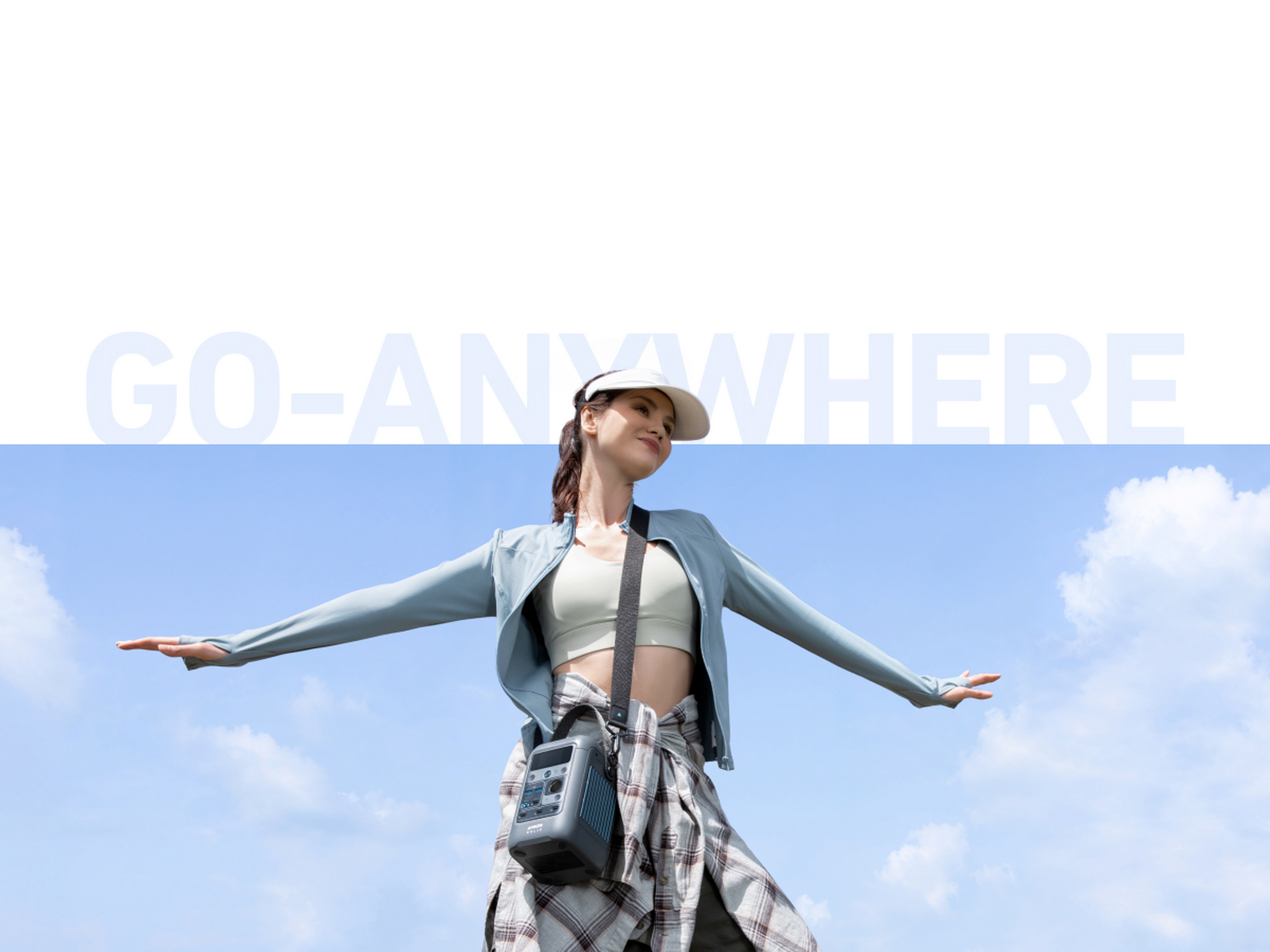 Kobieta w białej czapce i jasnoniebieskiej kurtce trzyma mały głośnik przenośny na tle błękitnego nieba.