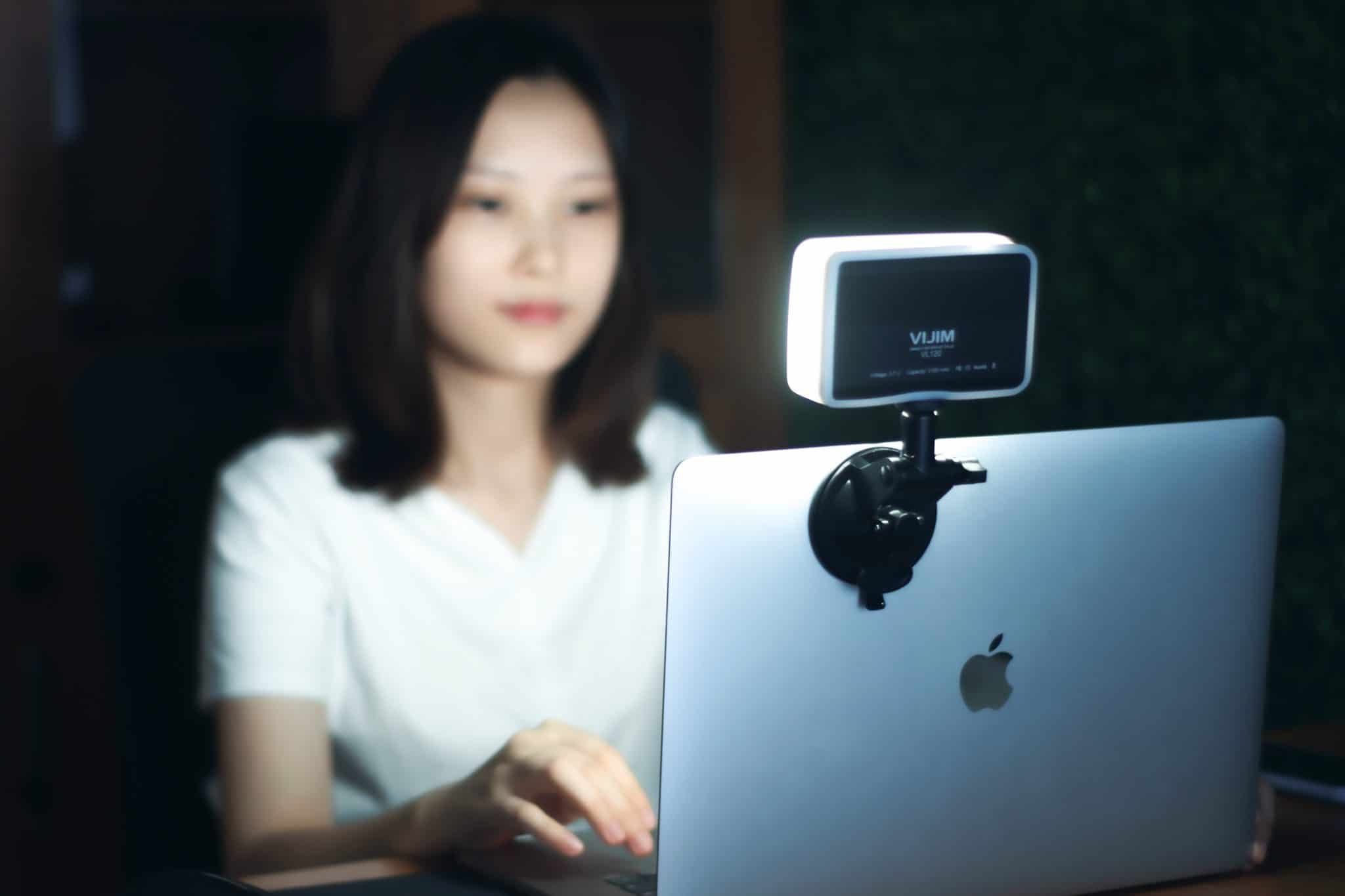 Eine Frau benutzt einen Laptop mit einem kleinen Licht daran. Das Licht ist weiß.