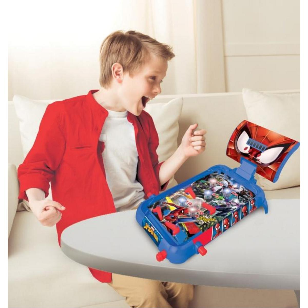 Ein Junge spielt einen Spider-Man Flipper. Er ist aufgeregt und die Maschine ist blau.