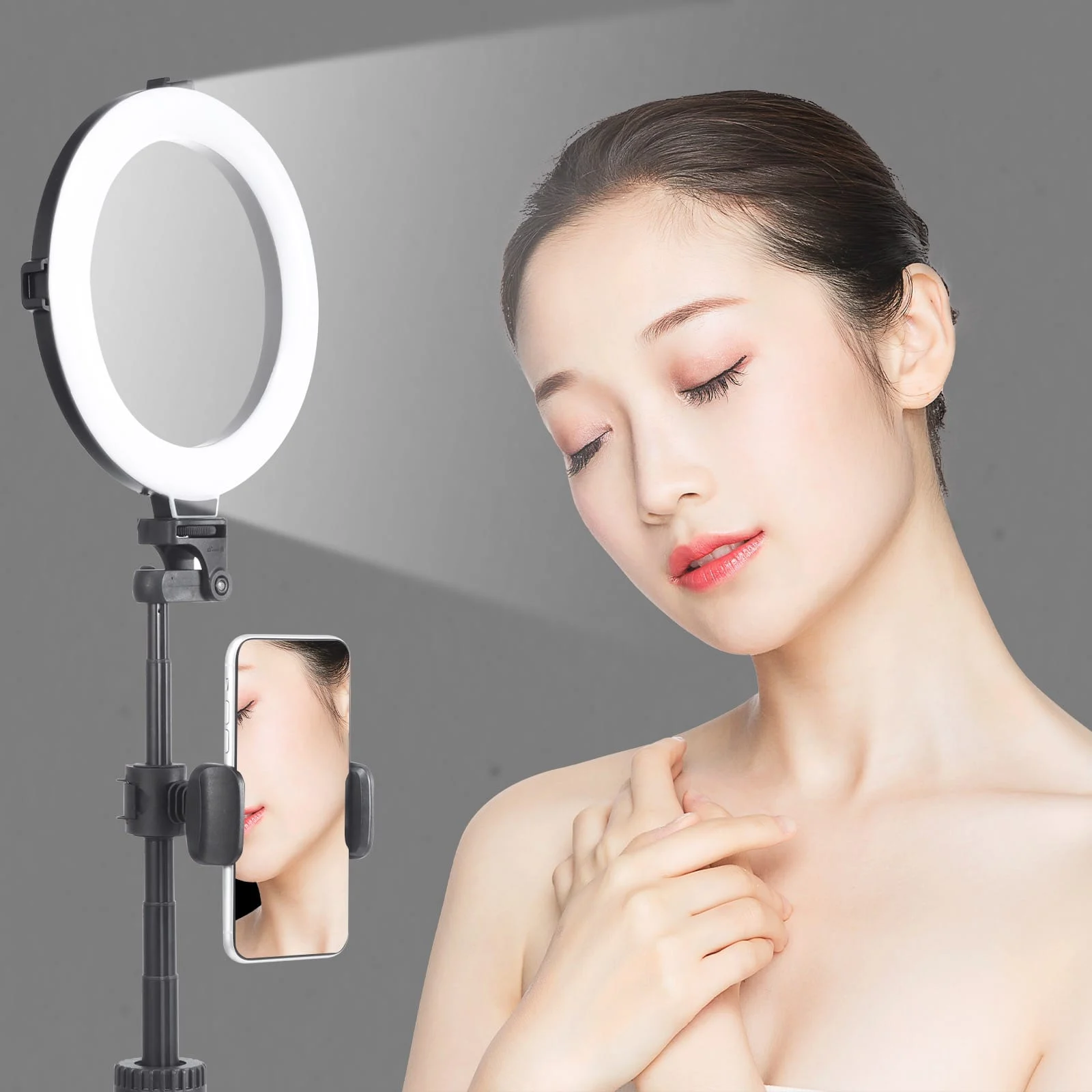 A woman with a beauty ring light and a phone. The phone shows the woman's face. The light is on.