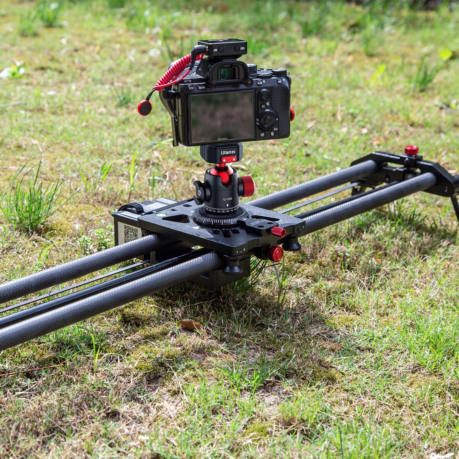 Een camera gemonteerd op een schuifrail op gras. Rode knoppen zichtbaar.