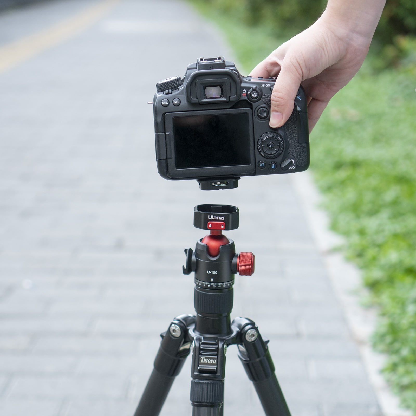 Camera wordt op een statief gemonteerd. De camera is zwart met een lens bevestigd, en het statief is zwart.