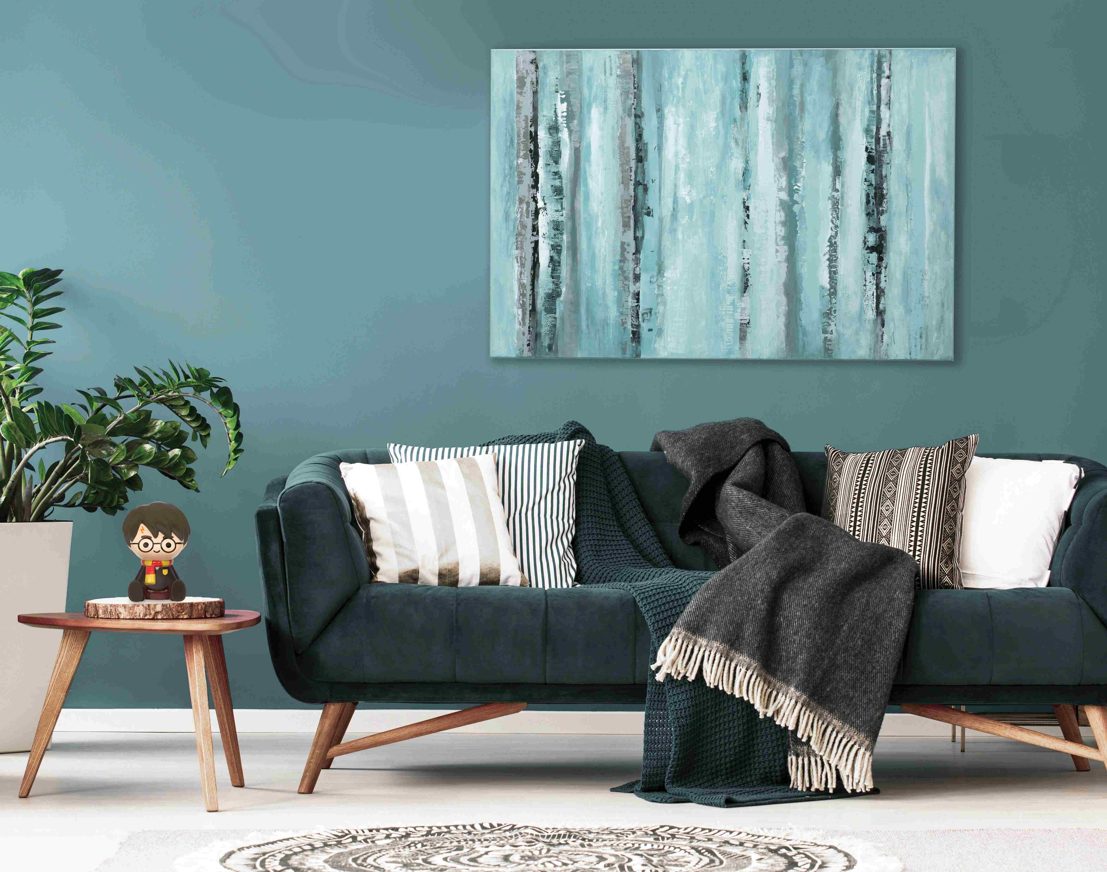 Wohnzimmer mit türkisfarbener Wand, Gemälde, Sofa und Beistelltisch.