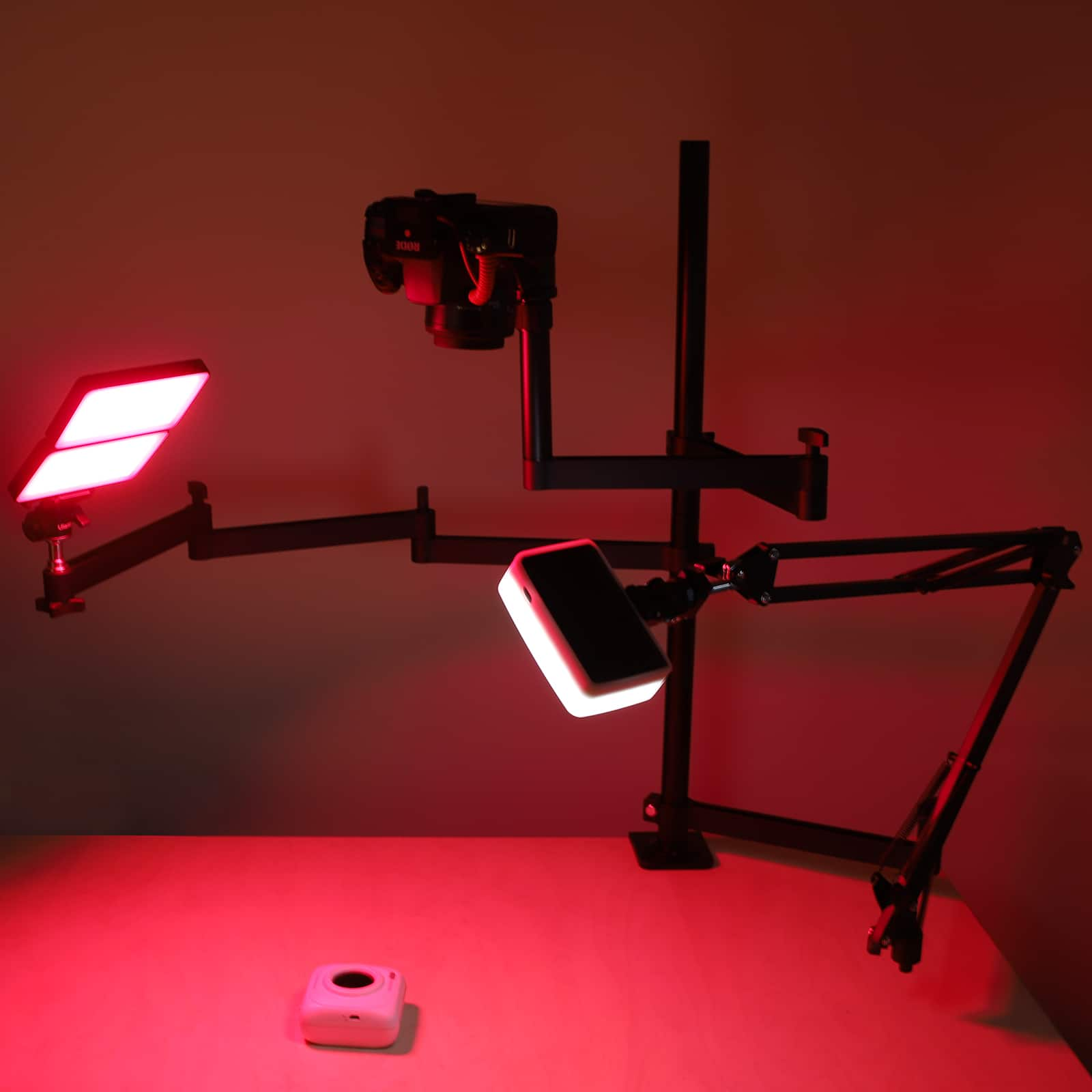 Studio setup with lights and camera. Red lighting. White table. All on black stands.