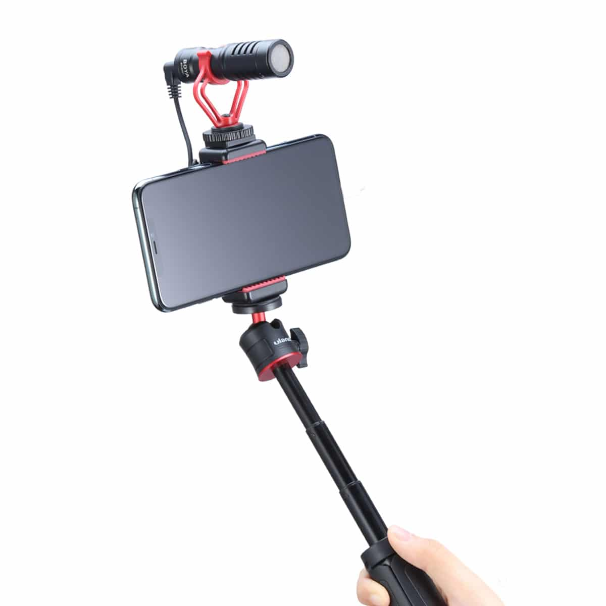 Telefon z dołączonym mikrofonem na kijku do selfie, trzymany w dłoni.