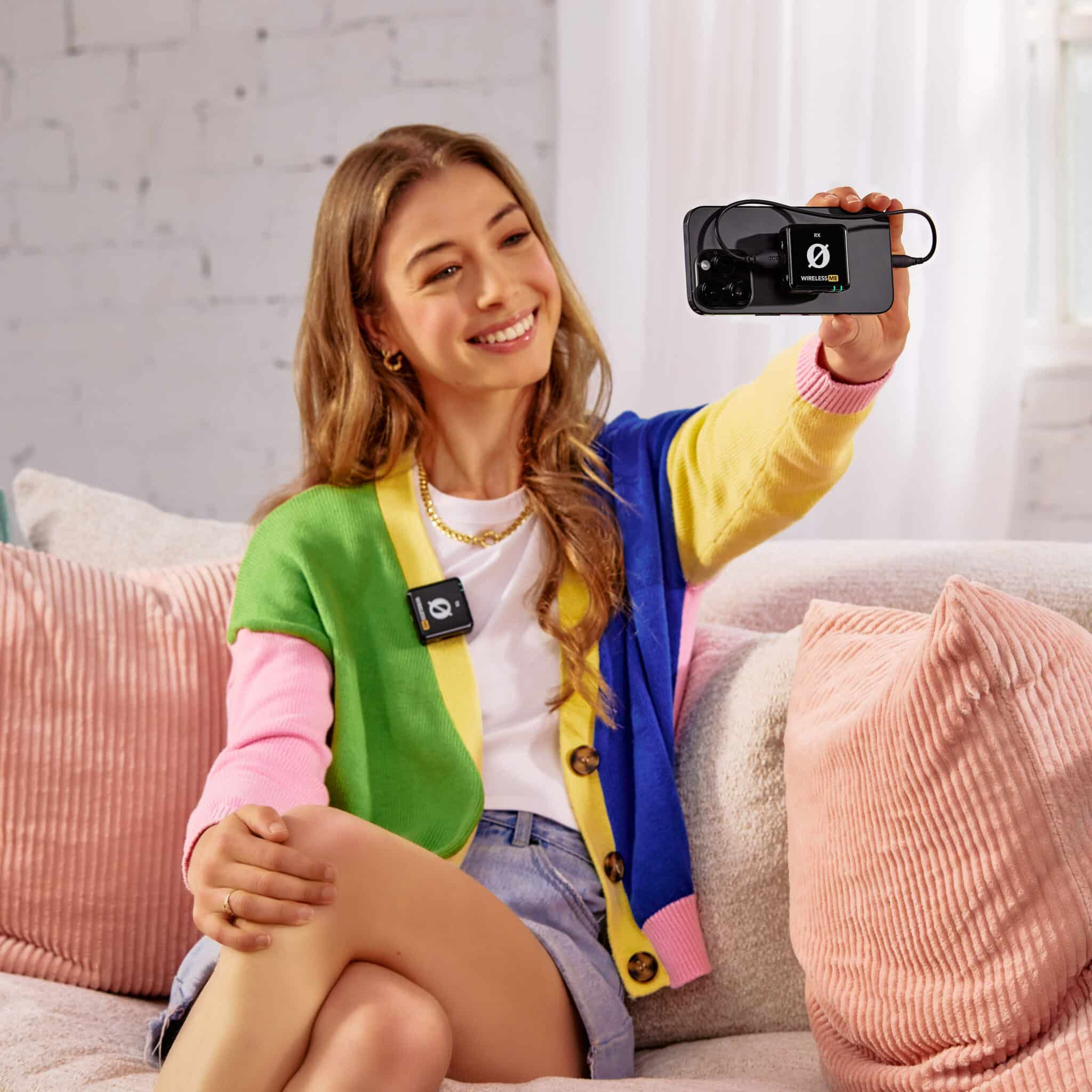 Kobieta uśmiecha się, trzymając telefon z podłączonym mikrofonem bezprzewodowym.