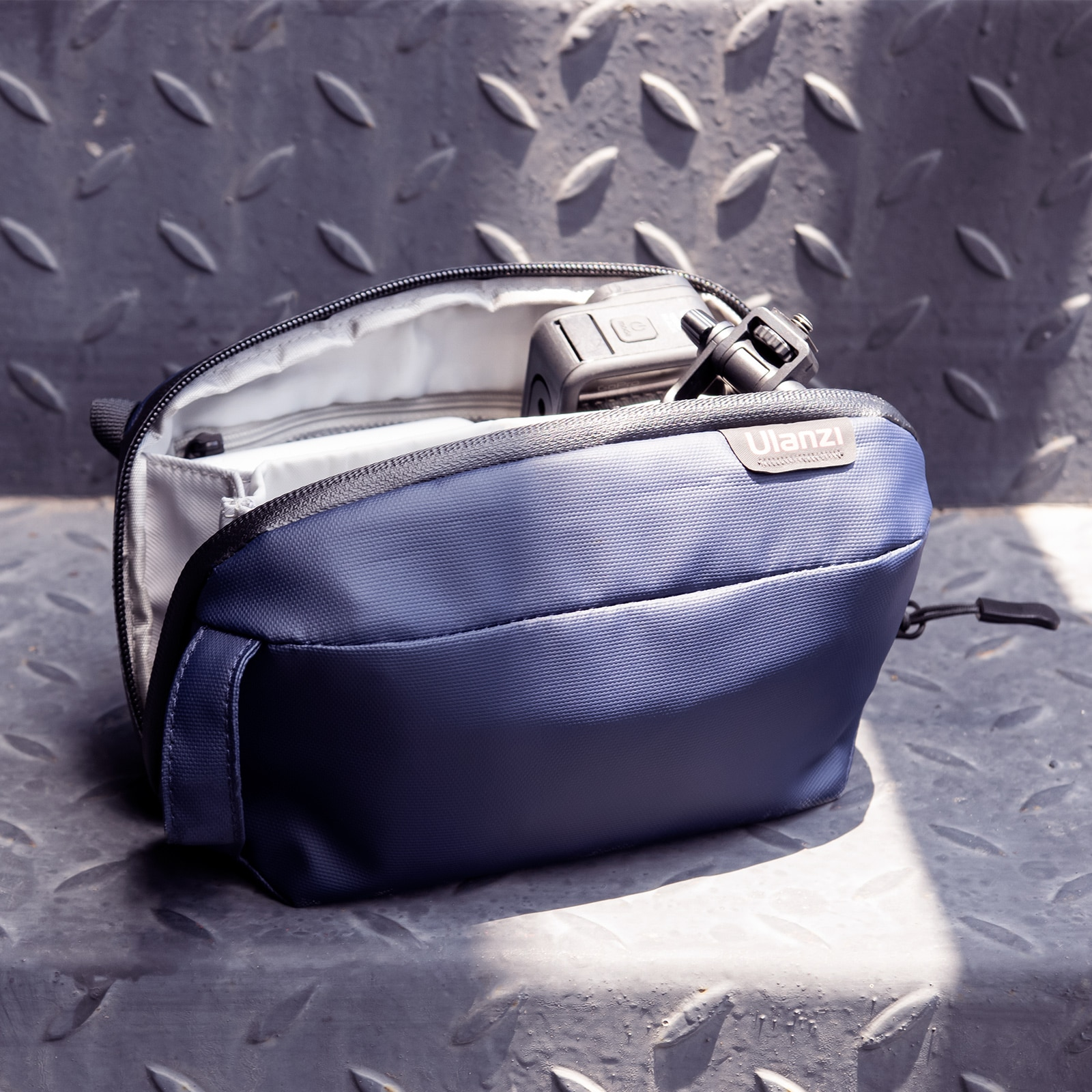 Un sac d'appareil photo bleu ouvert sur une surface métallique avec un appareil photo à l'intérieur.