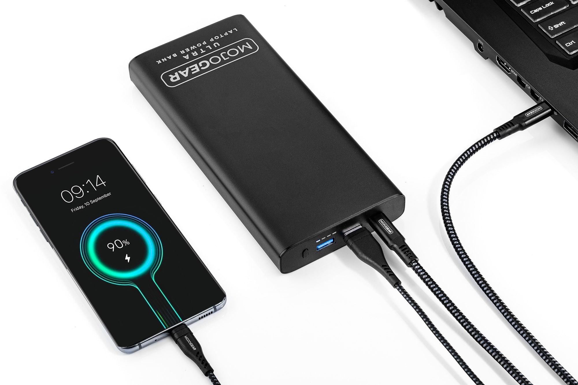 Een zwarte powerbank die een telefoon en een laptop oplaadt. De powerbank heeft een wit MOJOGEAR logo.
