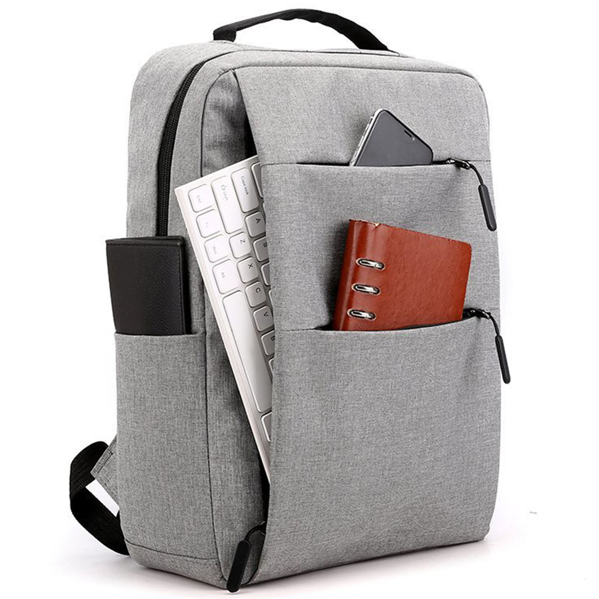 Ein grauer Rucksack mit Tastatur, Geldbörse, Telefon und Notizbuch in den Taschen, vor weißem Hintergrund.