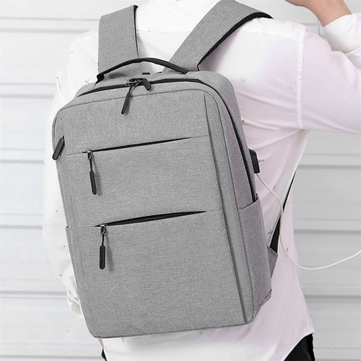 Grauer Rucksack mit mehreren Taschen, der von einem Mann getragen wird.