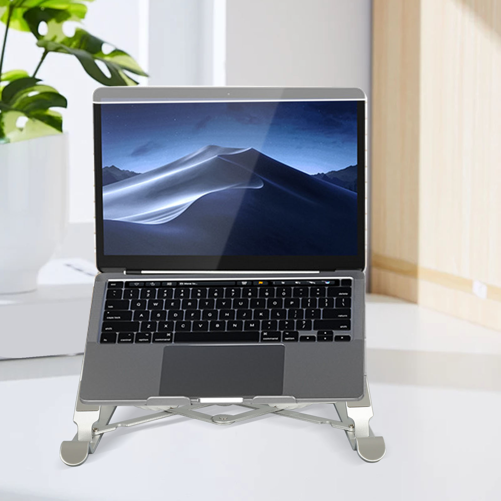 Laptop auf einem silbernen, faltbaren Ständer. Der Laptop-Bildschirm ist sichtbar, und der Ständer steht auf einem weißen Schreibtisch.