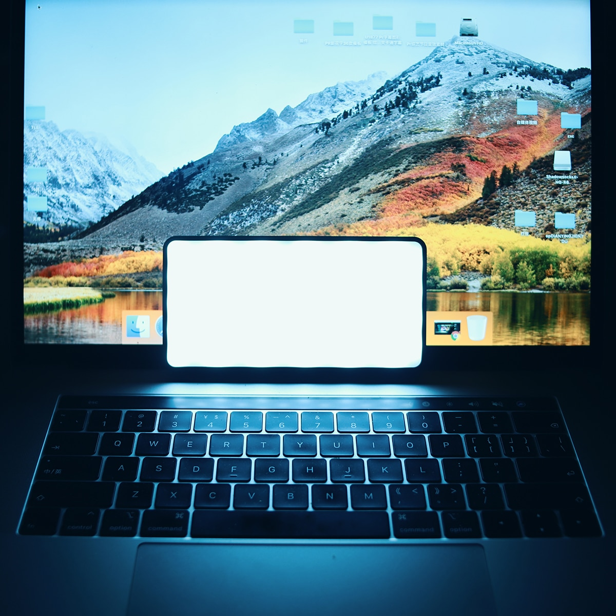 Laptop z jasnym ekranem pokazującym krajobraz górski i pusty, świecący prostokąt.