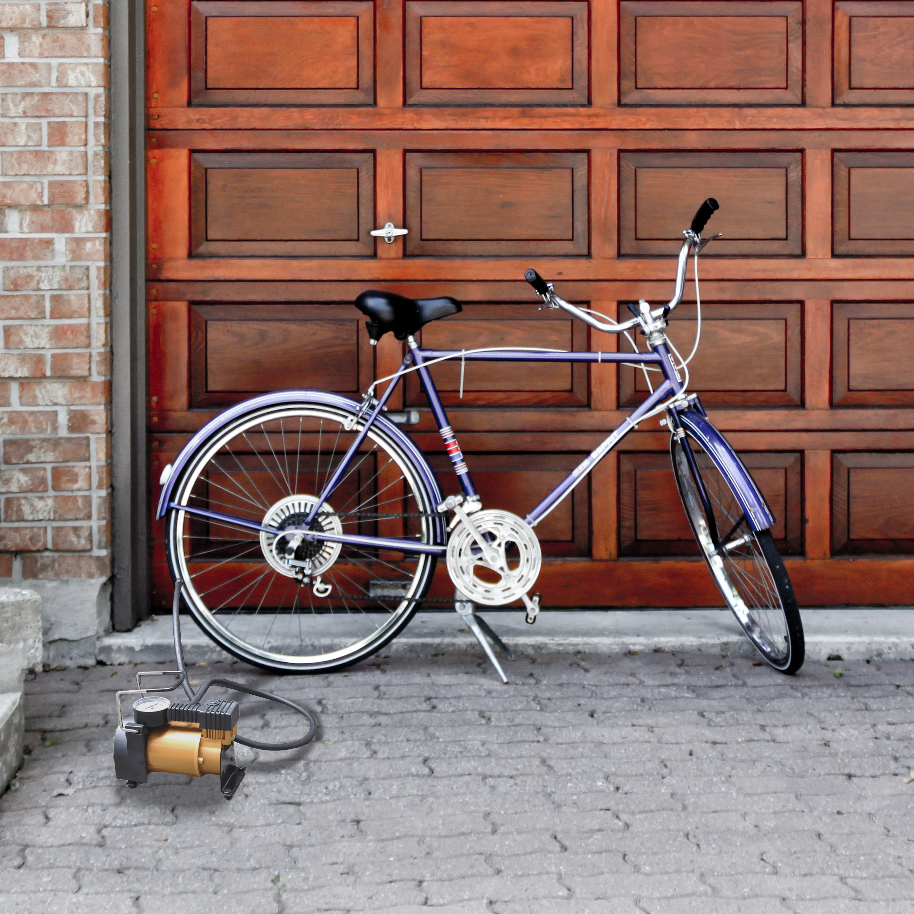 Una bicicletta viola appoggiata a una porta di garage in legno, con una pompa d'aria vicina.