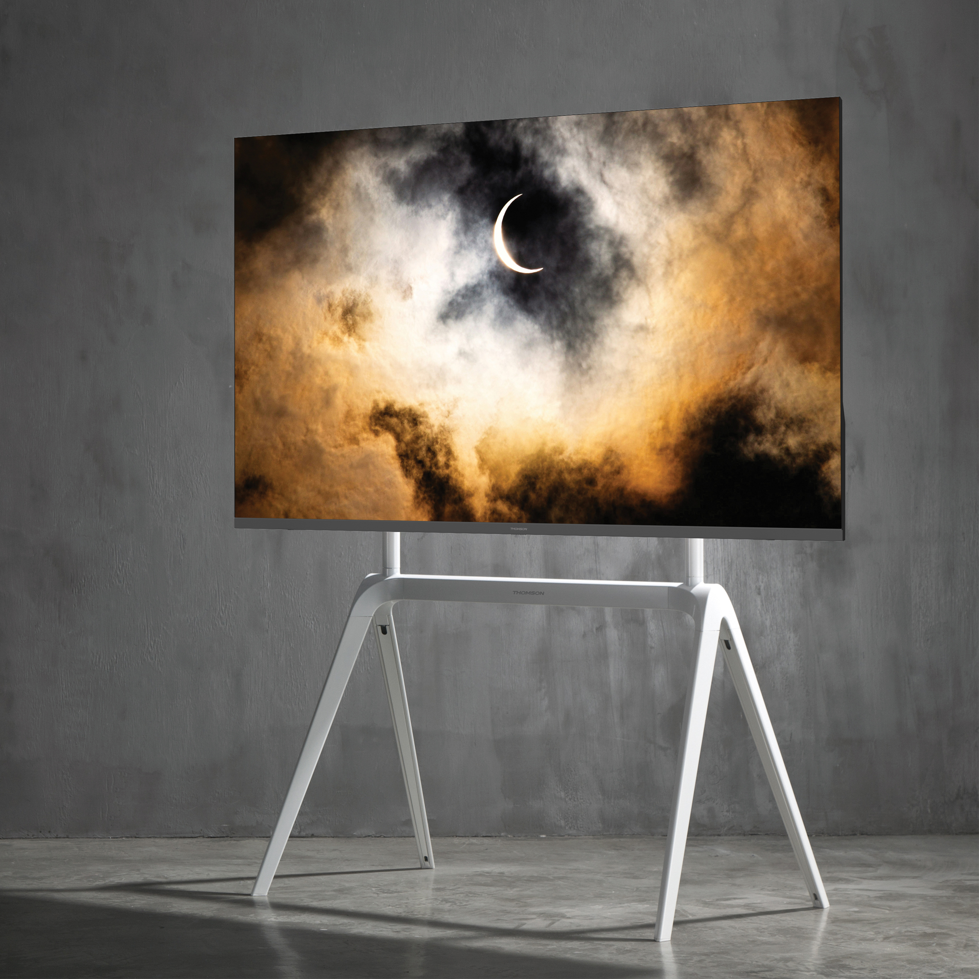 Una grande TV su un supporto bianco, che mostra un'immagine del sole oscurato dalle nuvole.