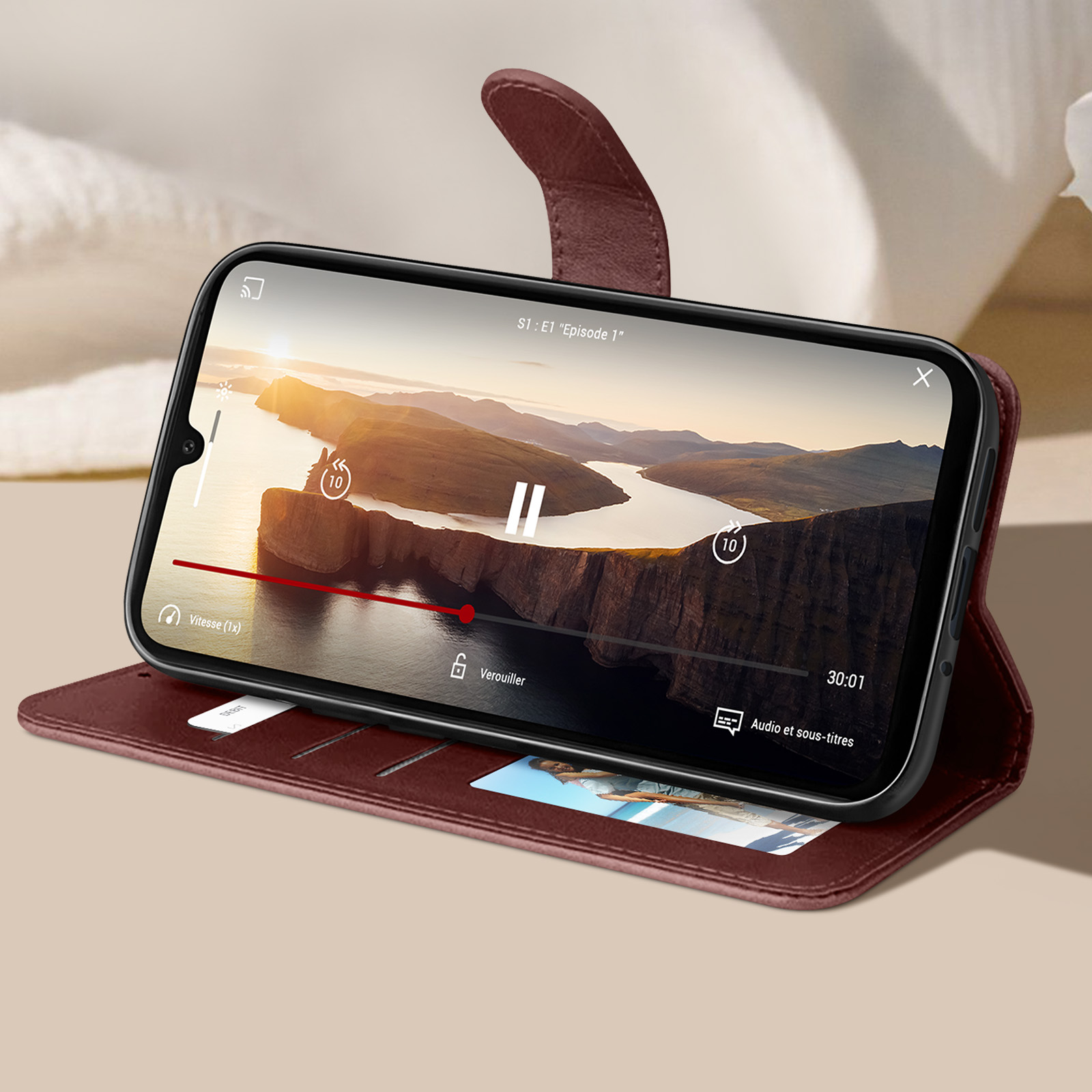 Uno smartphone mostra un video, all'interno di una custodia in pelle marrone, su sfondo chiaro.