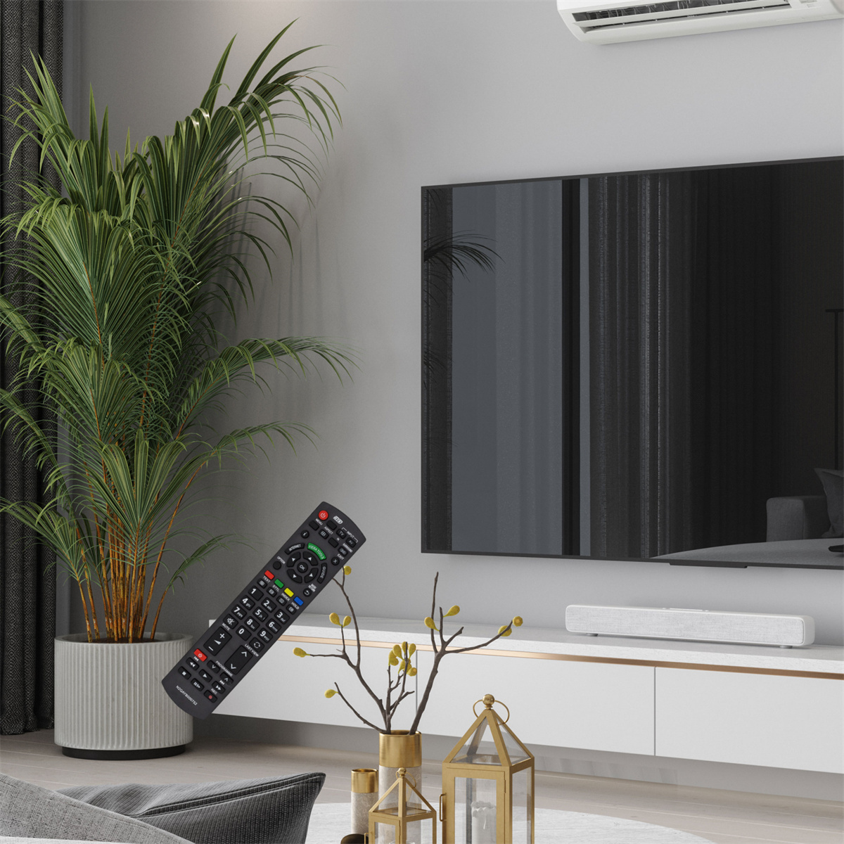 Wohnzimmer mit Fernseher, Pflanze, Fernbedienung und Dekorationen vor grauer Wand.