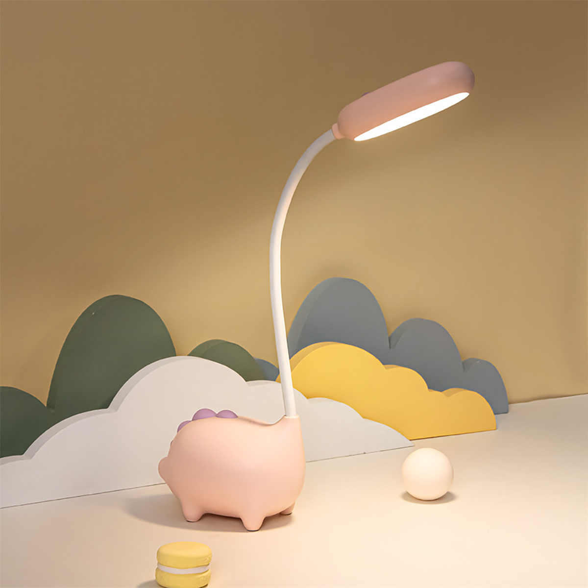 Eine rosa, schwein-förmige Schreibtischlampe mit gebogenem Hals, auf einem Schreibtisch.