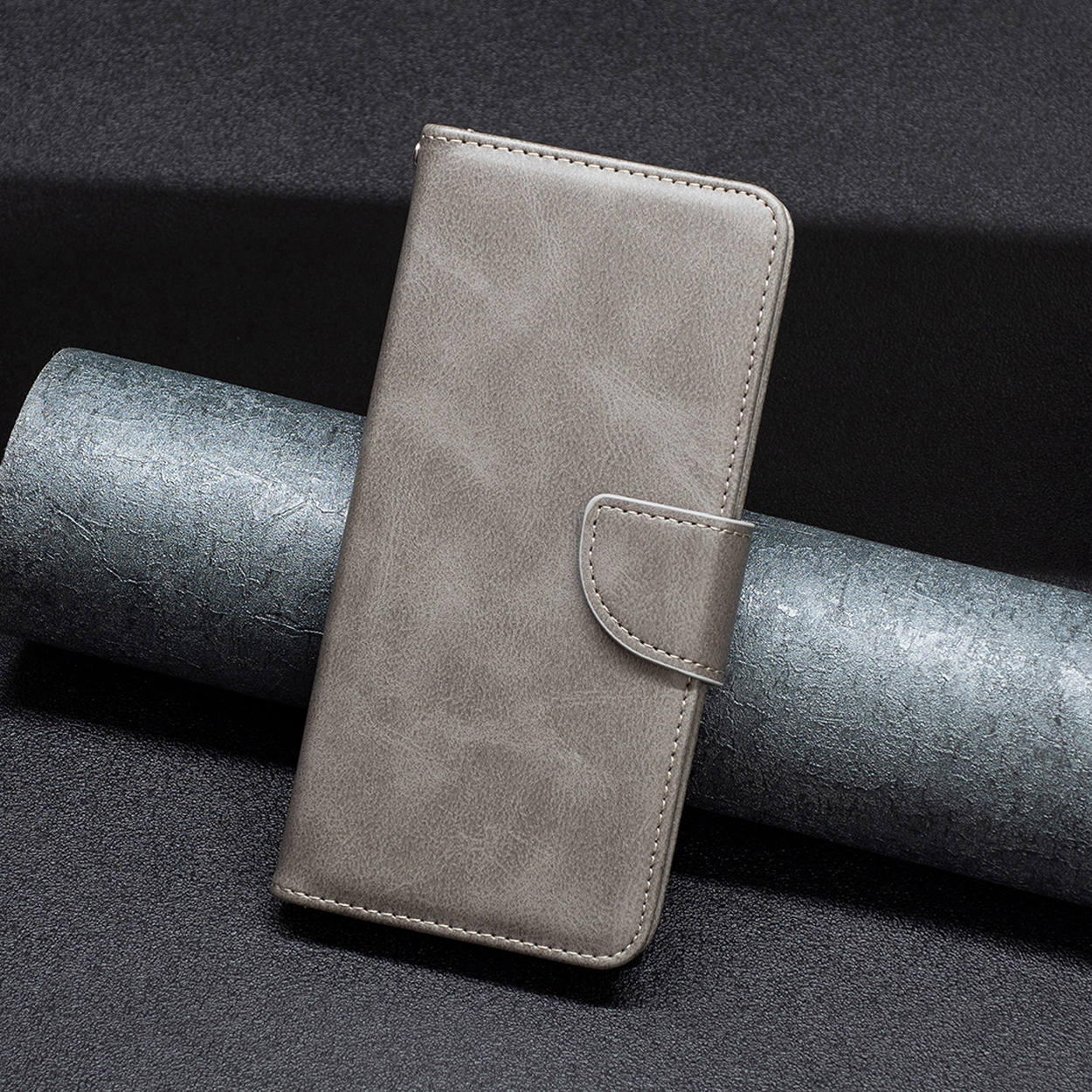 Grijze telefoonhoes met een magnetische sluiting. Hij is gesloten en ligt op een donker, getextureerd oppervlak.