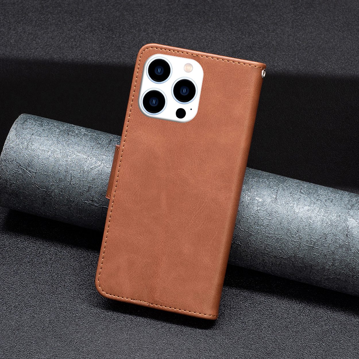Étui de téléphone marron fermé, montrant une découpe de caméra et un rouleau de papier gris.
