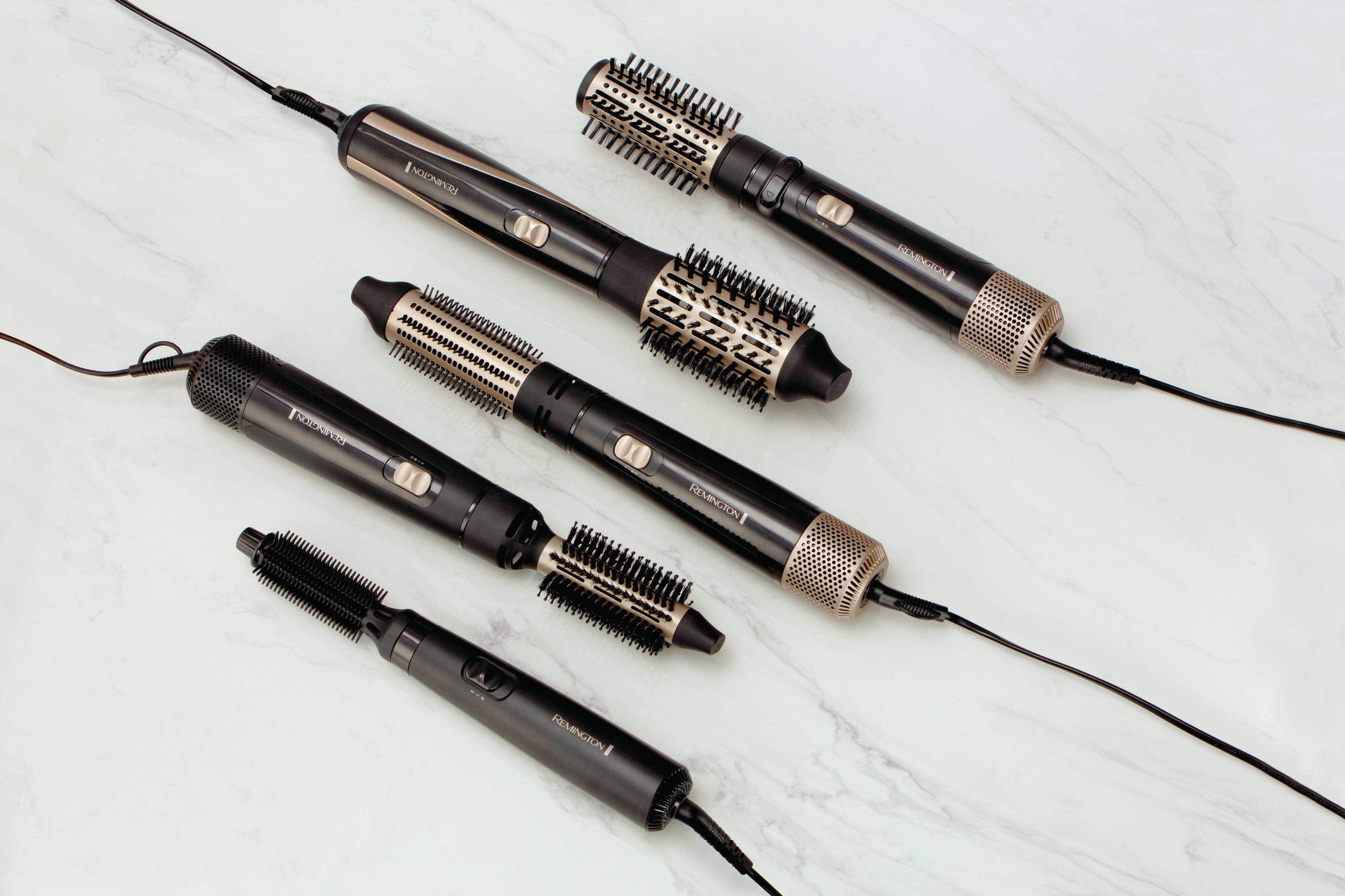 Sześć czarnych i złotych stylizatorów włosów o różnych kształtach ułożonych na marmurowej powierzchni.