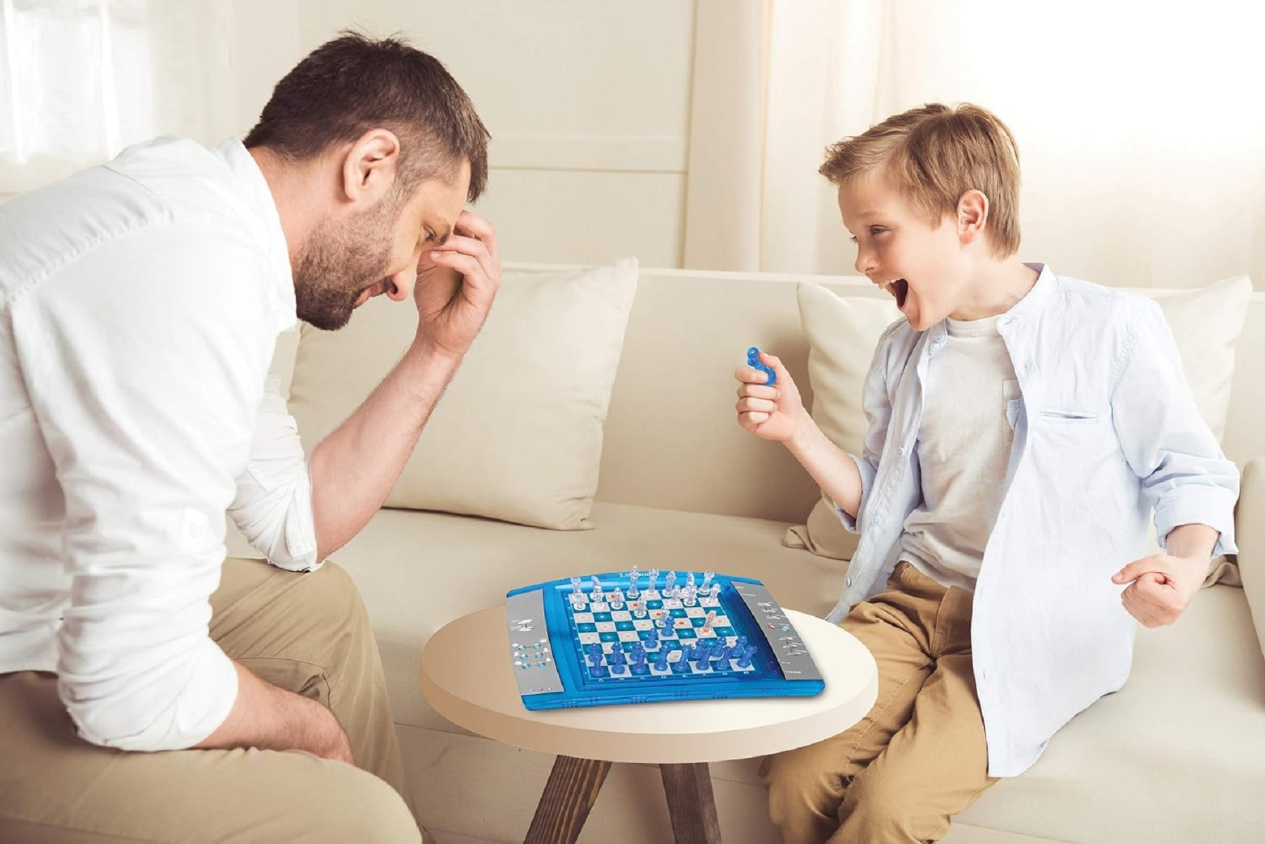 Mężczyzna i chłopiec grają w grę planszową. Mężczyzna wygląda na sfrustrowanego, chłopiec podekscytowanego. Gra jest niebieska.