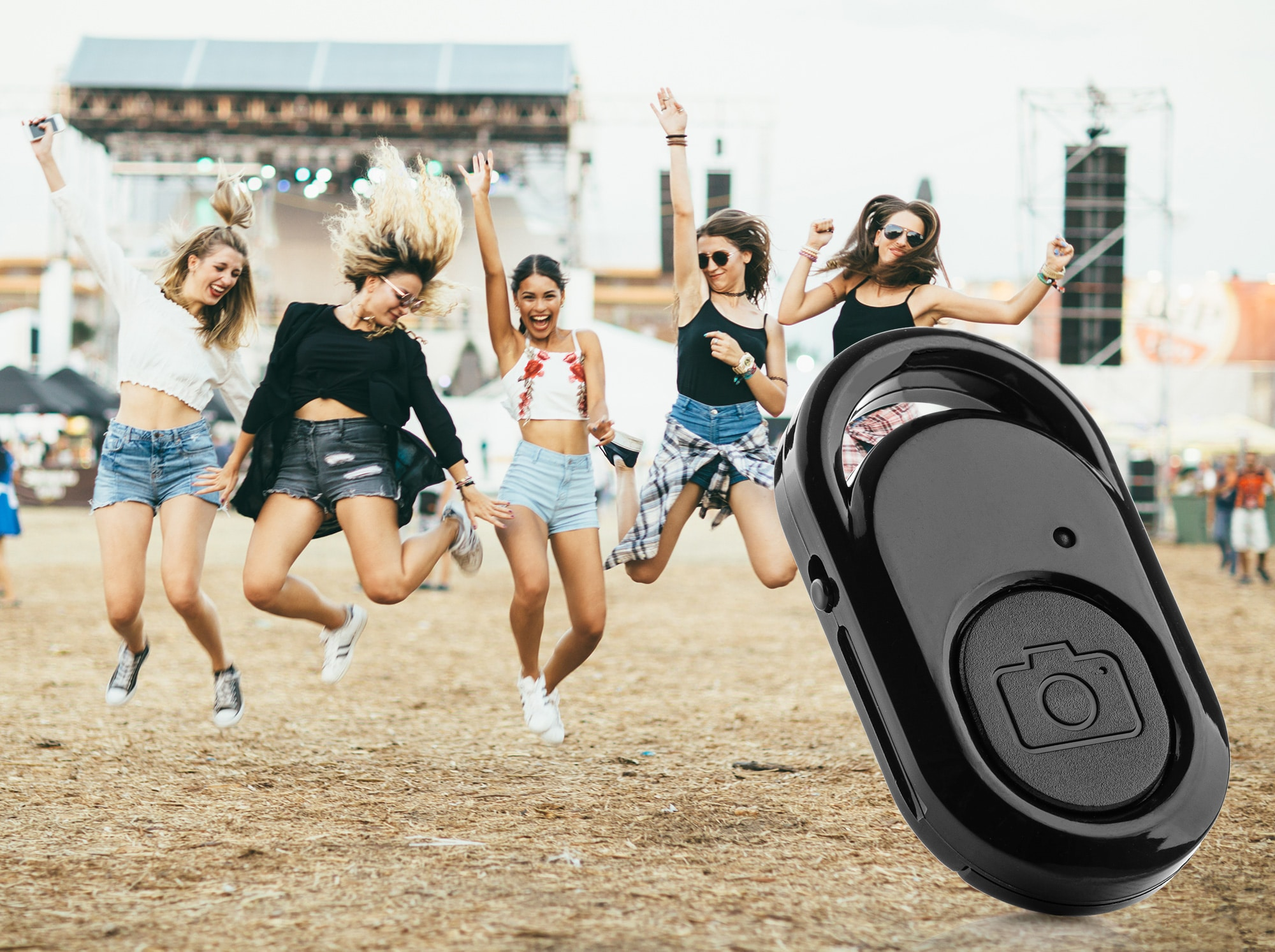 Four people jumping in the air, with a black remote control in the foreground.