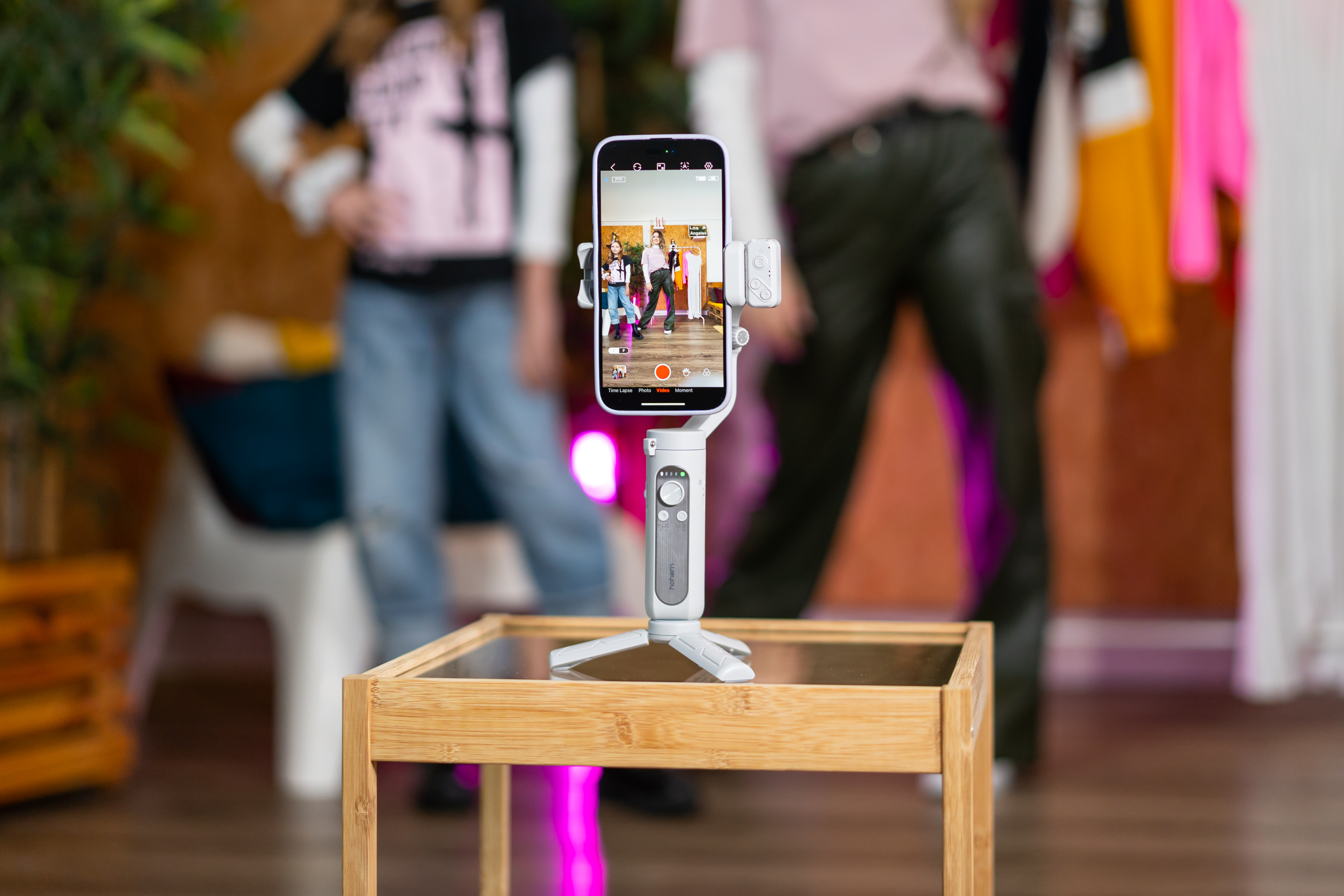 A person filming with a phone on a tripod. Another person is in the background.