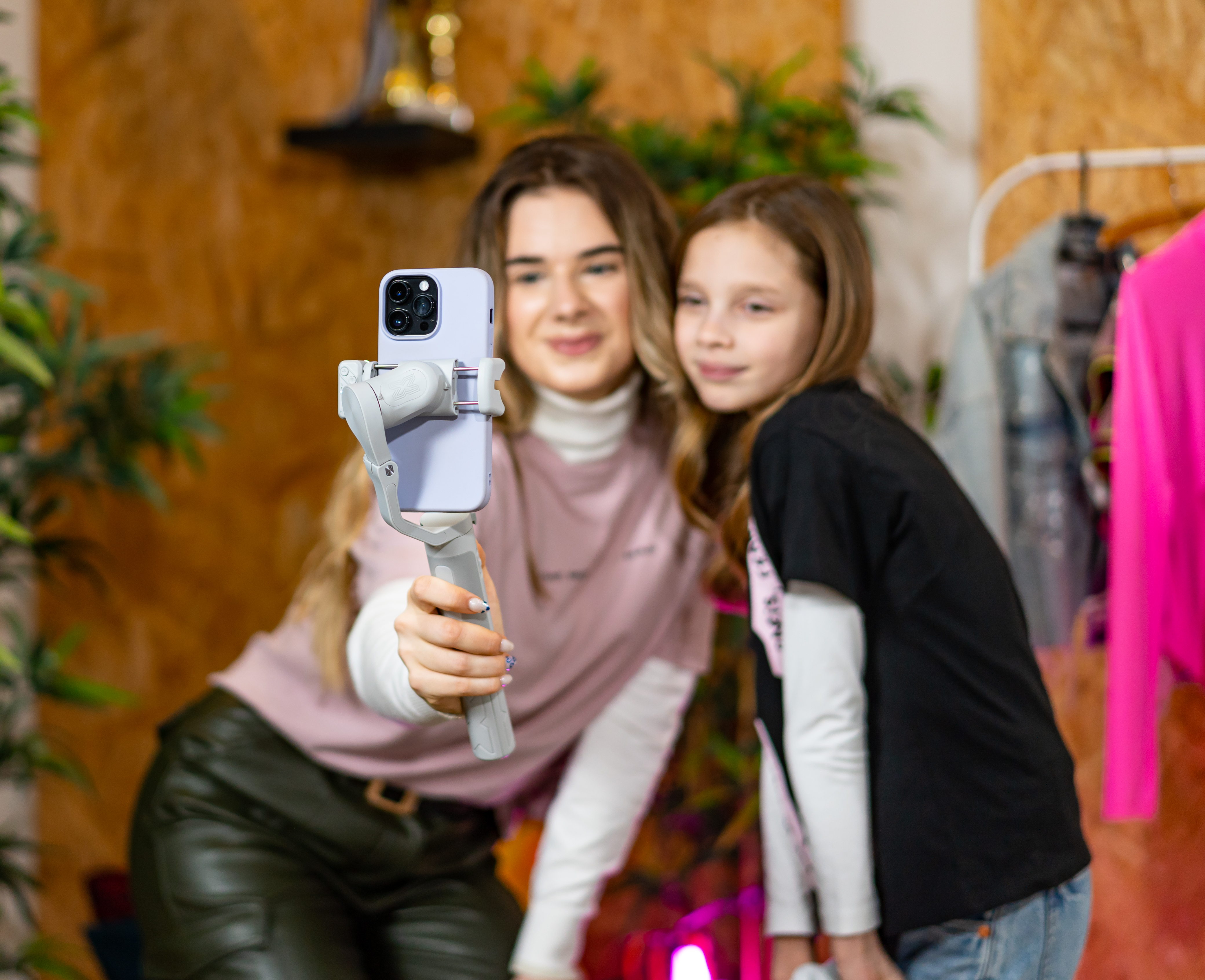 Two women and a girl taking a selfie with a phone on a gimbal. They are smiling.