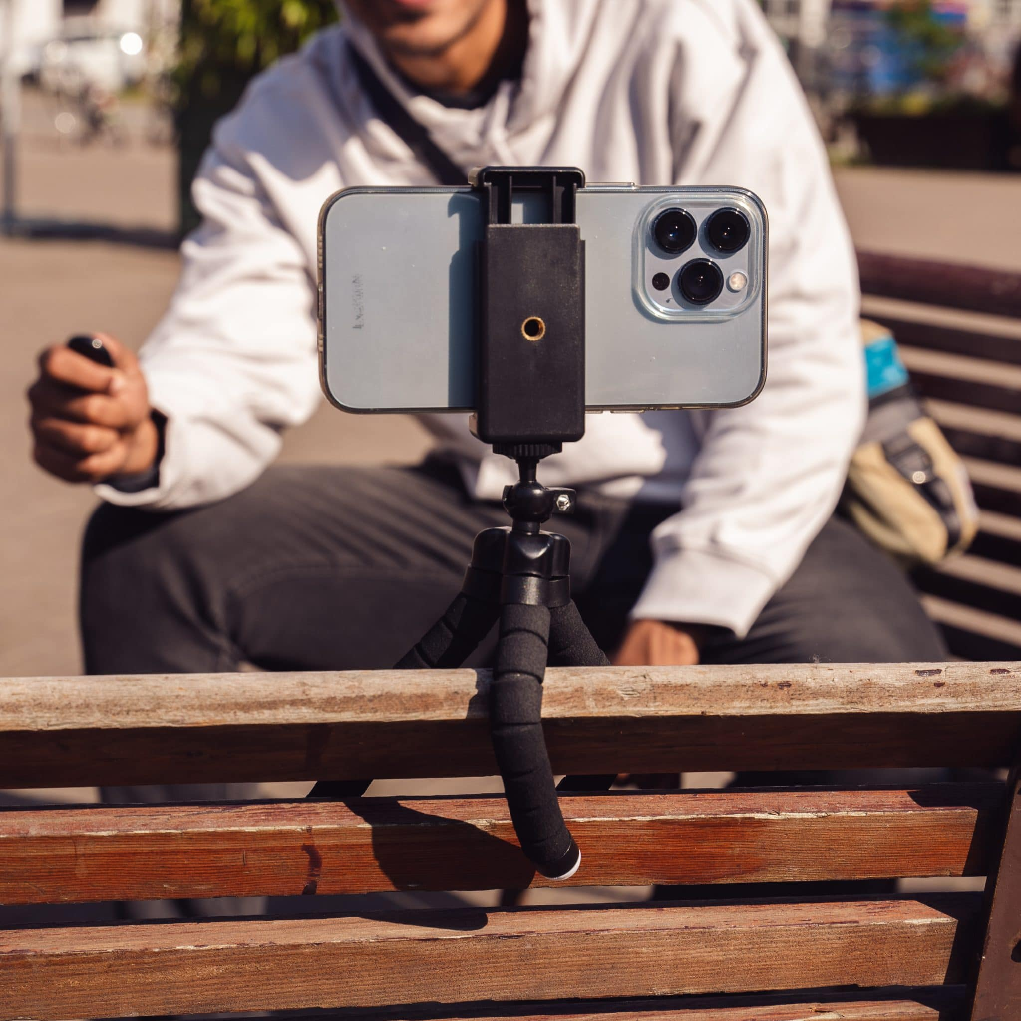 Een persoon die een telefoon op een statief vasthoudt, video opneemt. De telefoon is op een bank gemonteerd.