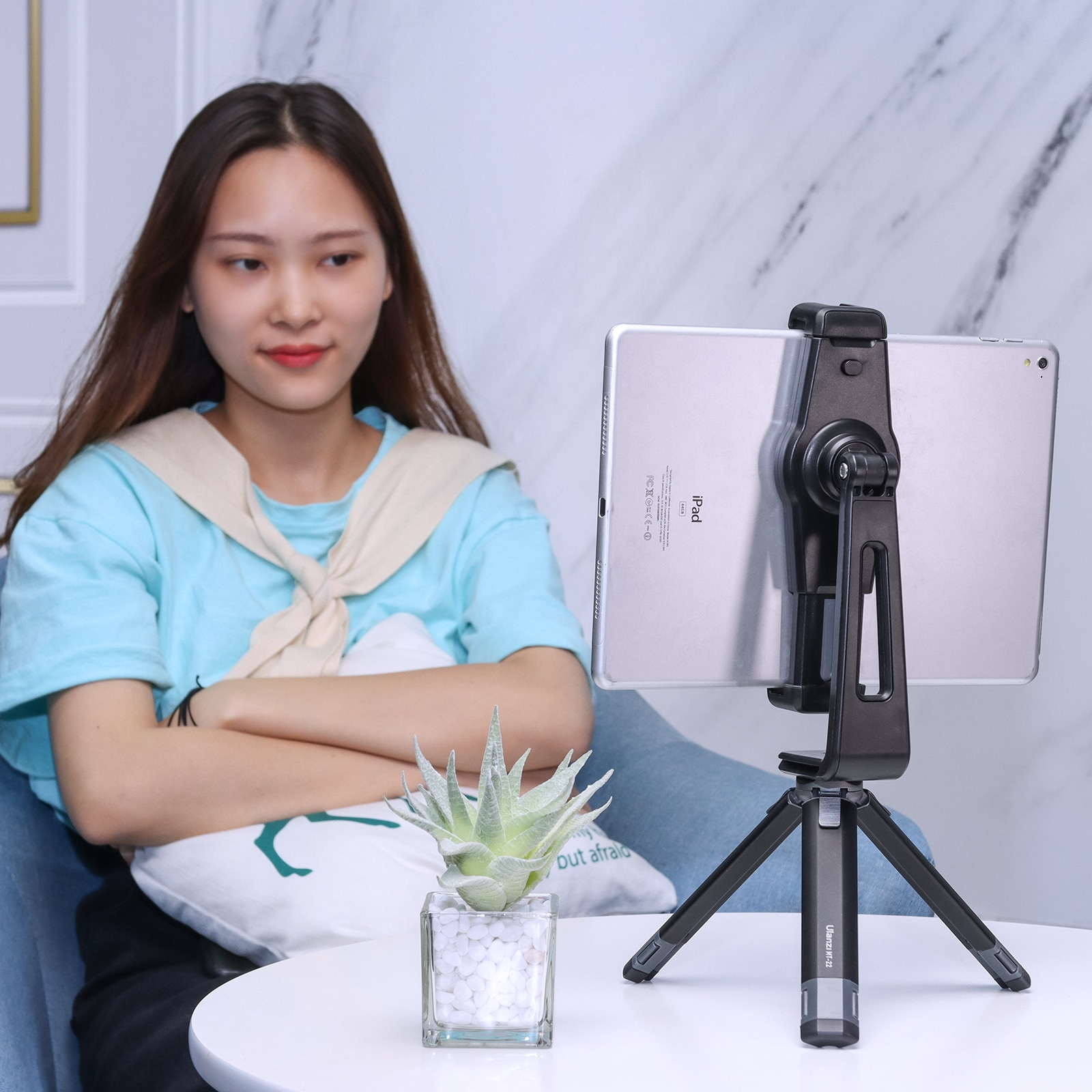 Kobieta siedzi z tabletem na statywie. Przed nią roślina.
