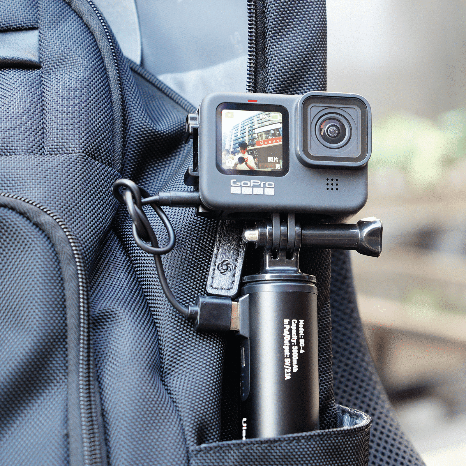 Une caméra GoPro attachée à un sac à dos avec un câble de chargement.