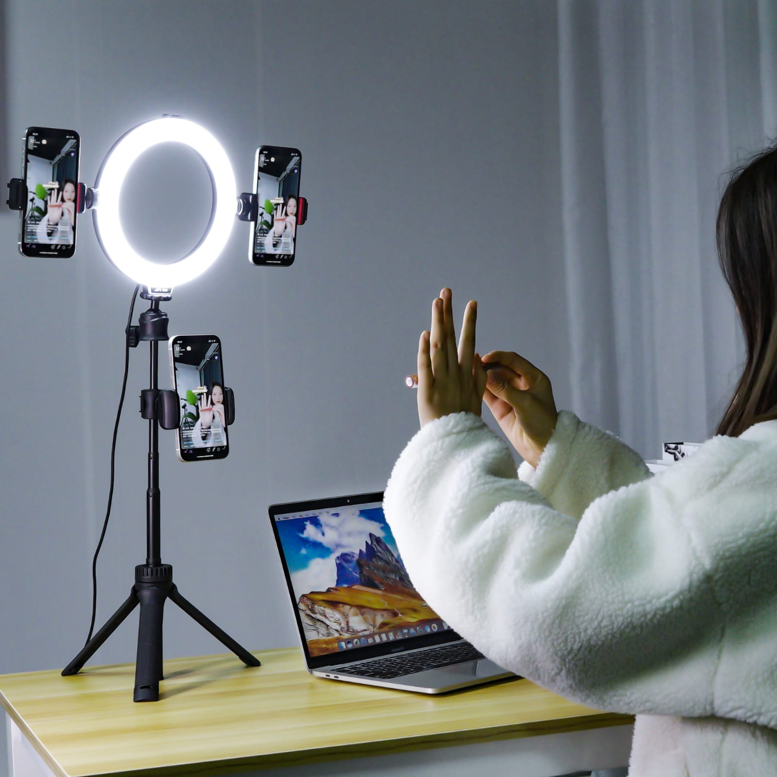 A ring light and several phones. A person is in front of a laptop and is gesturing.