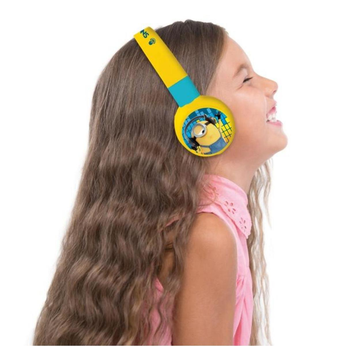 Ragazza con cuffie Minions gialle e blu, sorridente. Sfondo bianco.