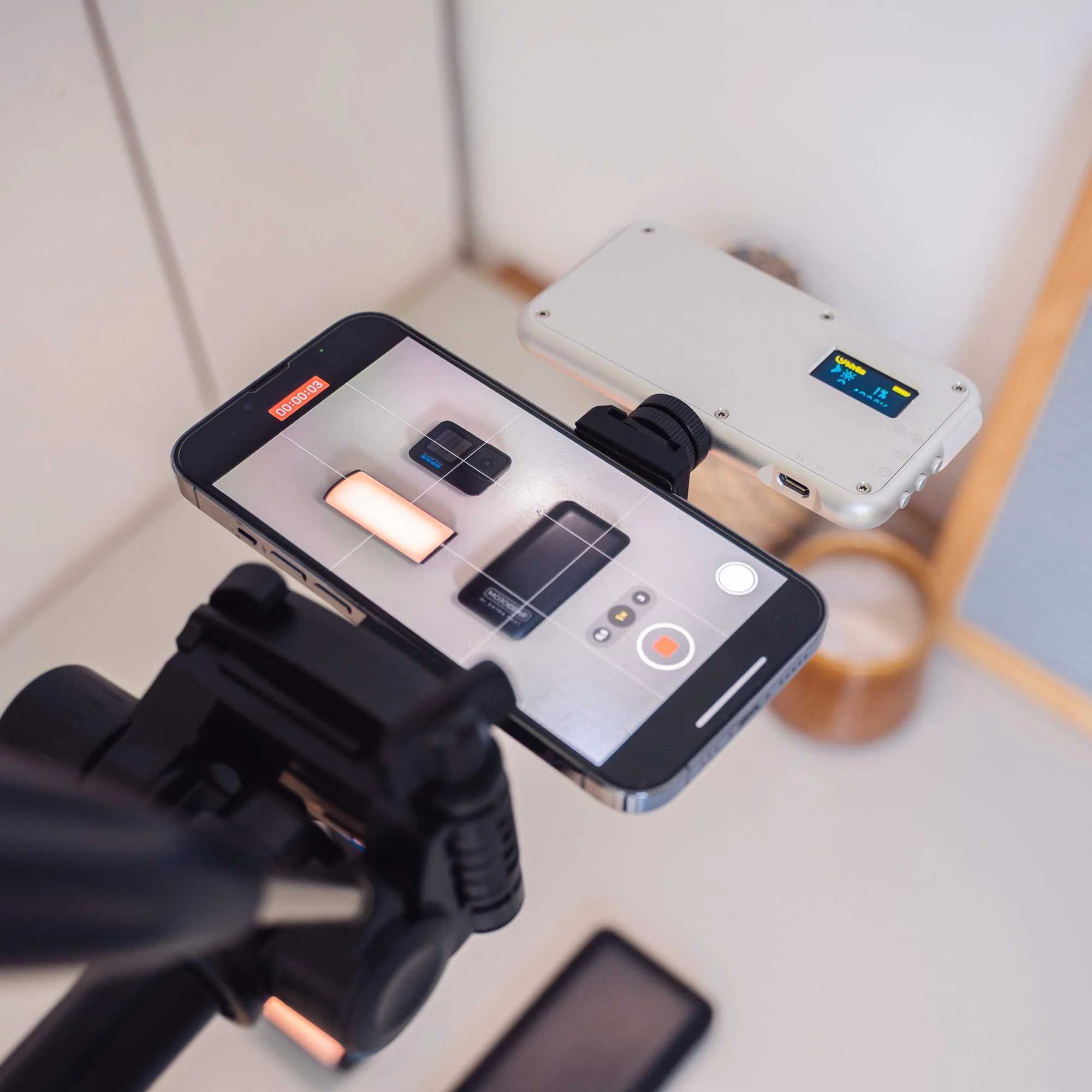 Een telefoon met een camera-app open, gemonteerd op een rig, met een lamp.