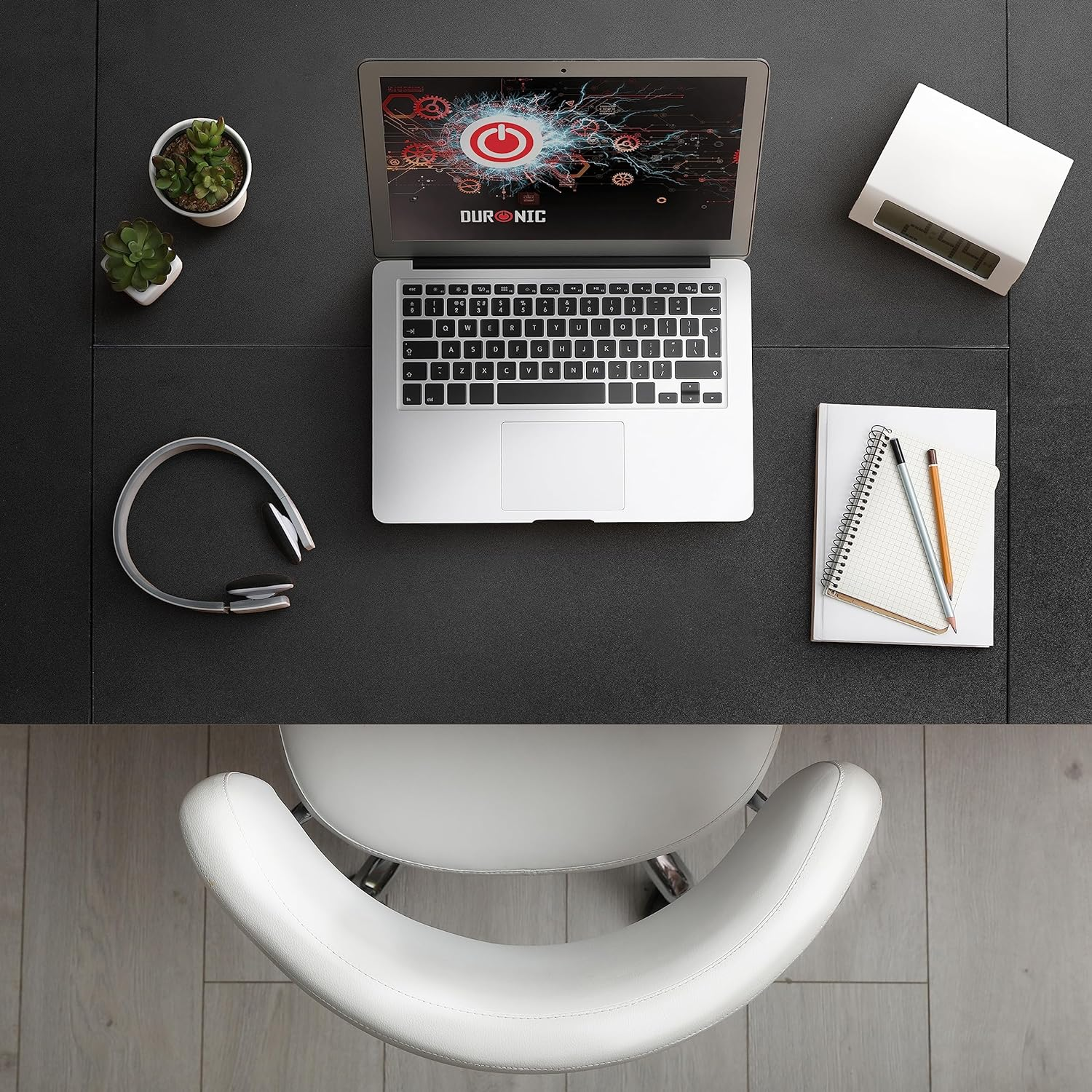 Schreibtisch mit Laptop mit Stromsymbol, Kopfhörern und anderem Büromaterial.