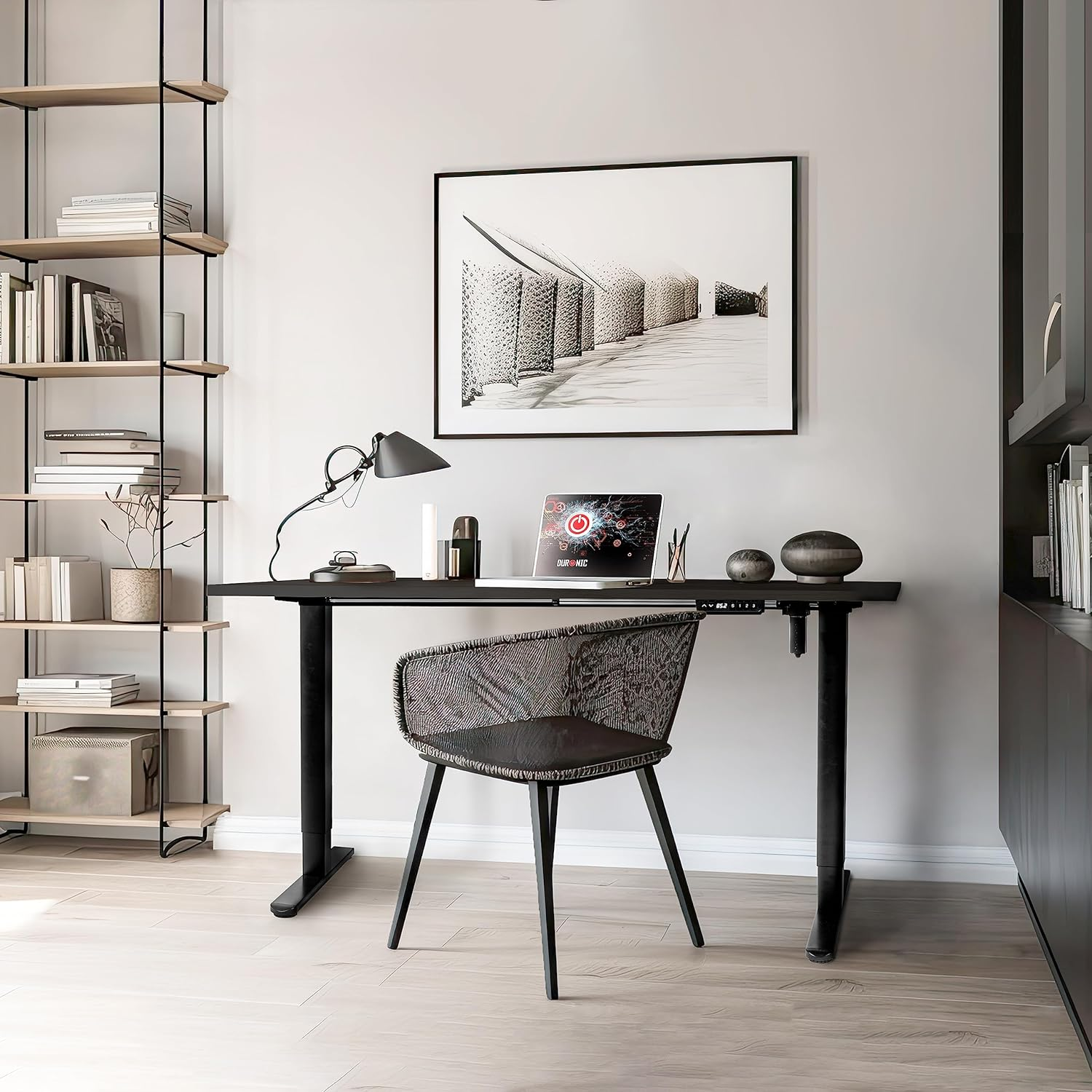 Modernes Büro mit schwarzem Schreibtisch, Stuhl und gerahmtem Bild. Bücherregal und Deko-Artikel sichtbar.