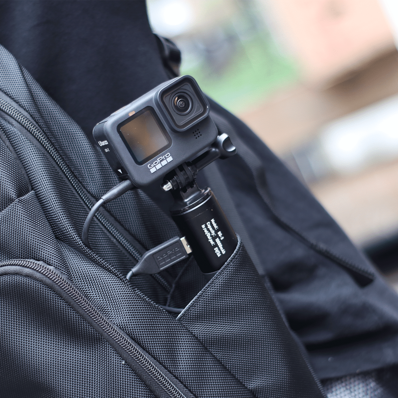 Een GoPro-camera is aan een rugzak bevestigd. Een USB-kabel is aangesloten.
