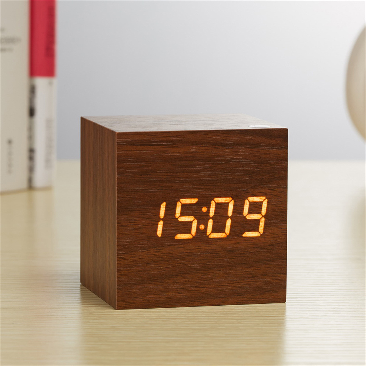 Holzwürfeluhr mit orangefarbenen Ziffern 15:09, auf hellem Holz.